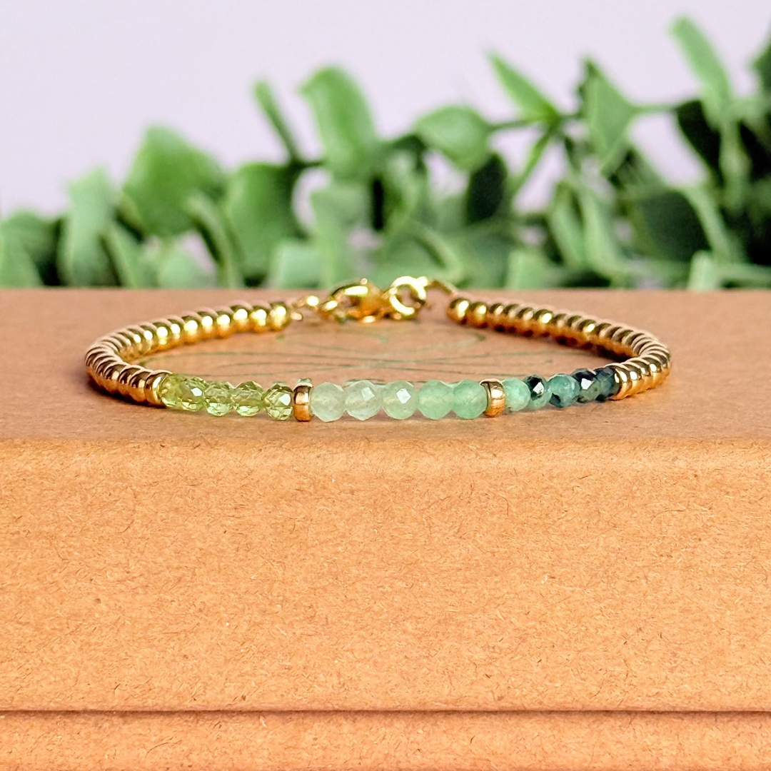 Dainty minimalist yellow gold filled crystal bracelet featuring 3mm faceted emerald, peridot and green aventurine beads in a colour block Ombre style. Fastens with a gold filled lobster clasp with an extender chain.