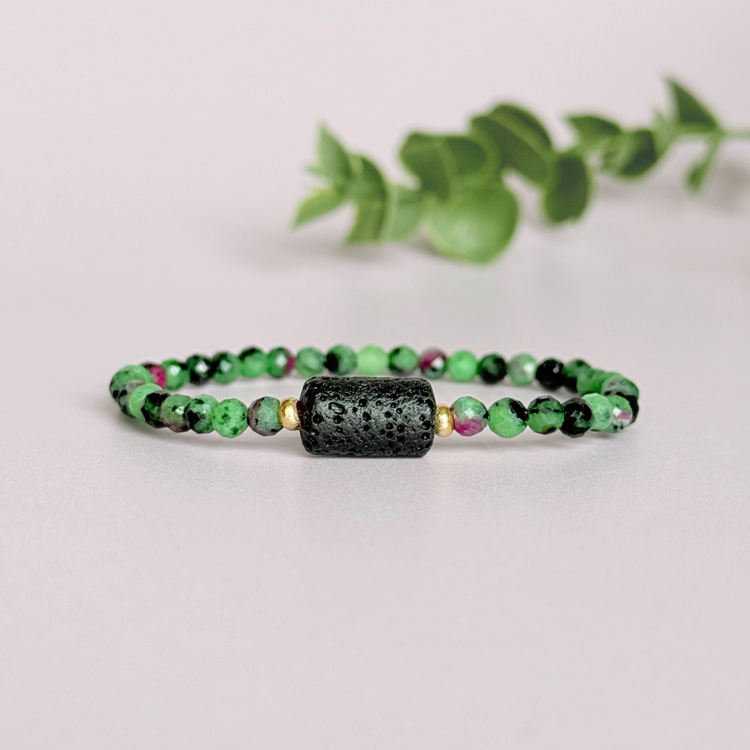Essential oil diffuser bracelet featuring black lava rock tube bead on the band of 4mm faceted ruby in zoisite beads. Finished with your choice of sterling silver or gold vermeil accent beads.
