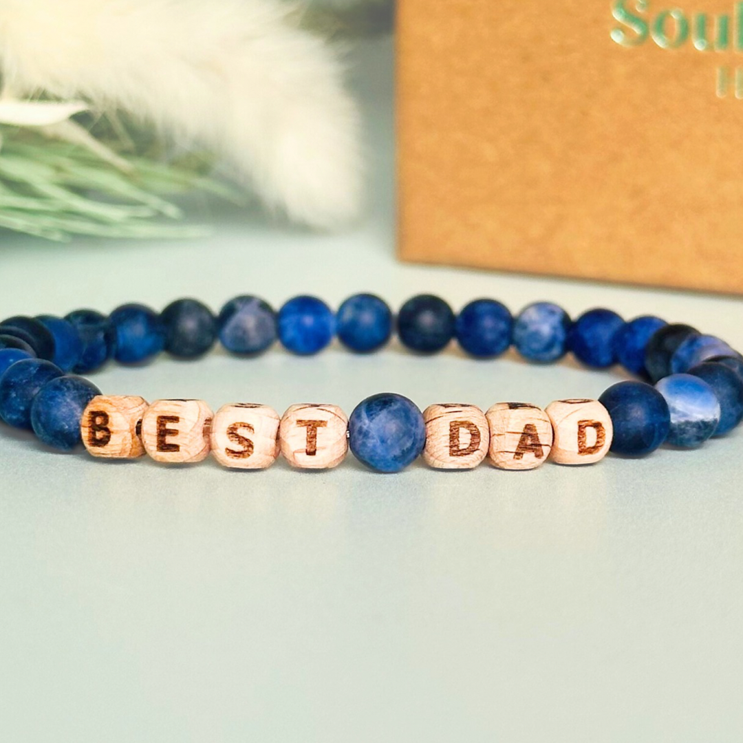 Men’s crystal bracelet with 6mm frosted sodalite gemstone crystal beads and laser engraved wooden letter beads featuring the words best dad or can also be made with any other words or letters.