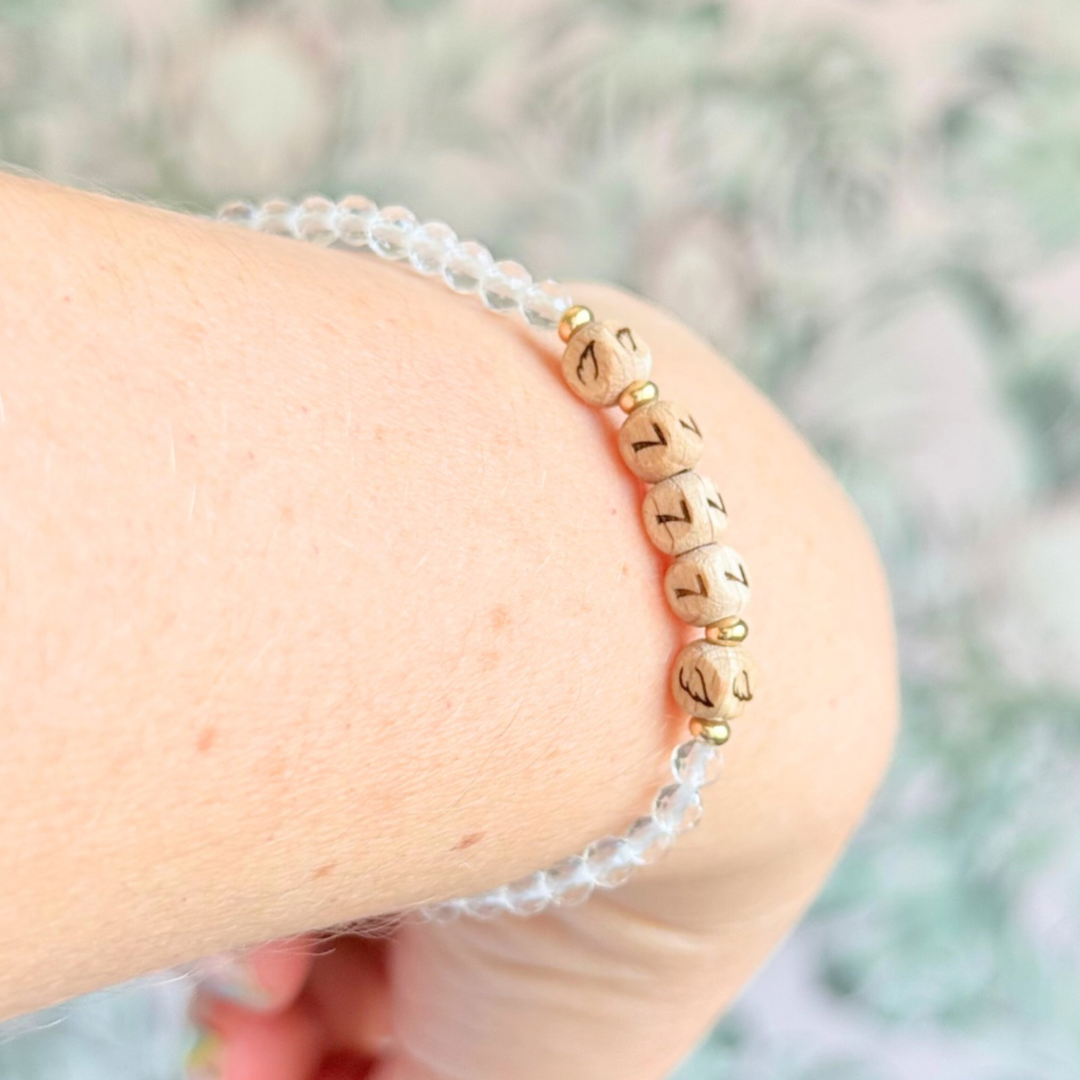 Bracelet featuring engraved wooden 777 angel number and wing beads, on the band of 4mm faceted clear quartz round crystal gemstone beads. Finished with your choice of gold vermeil, sterling silver or rose gold vermeil accent beads.