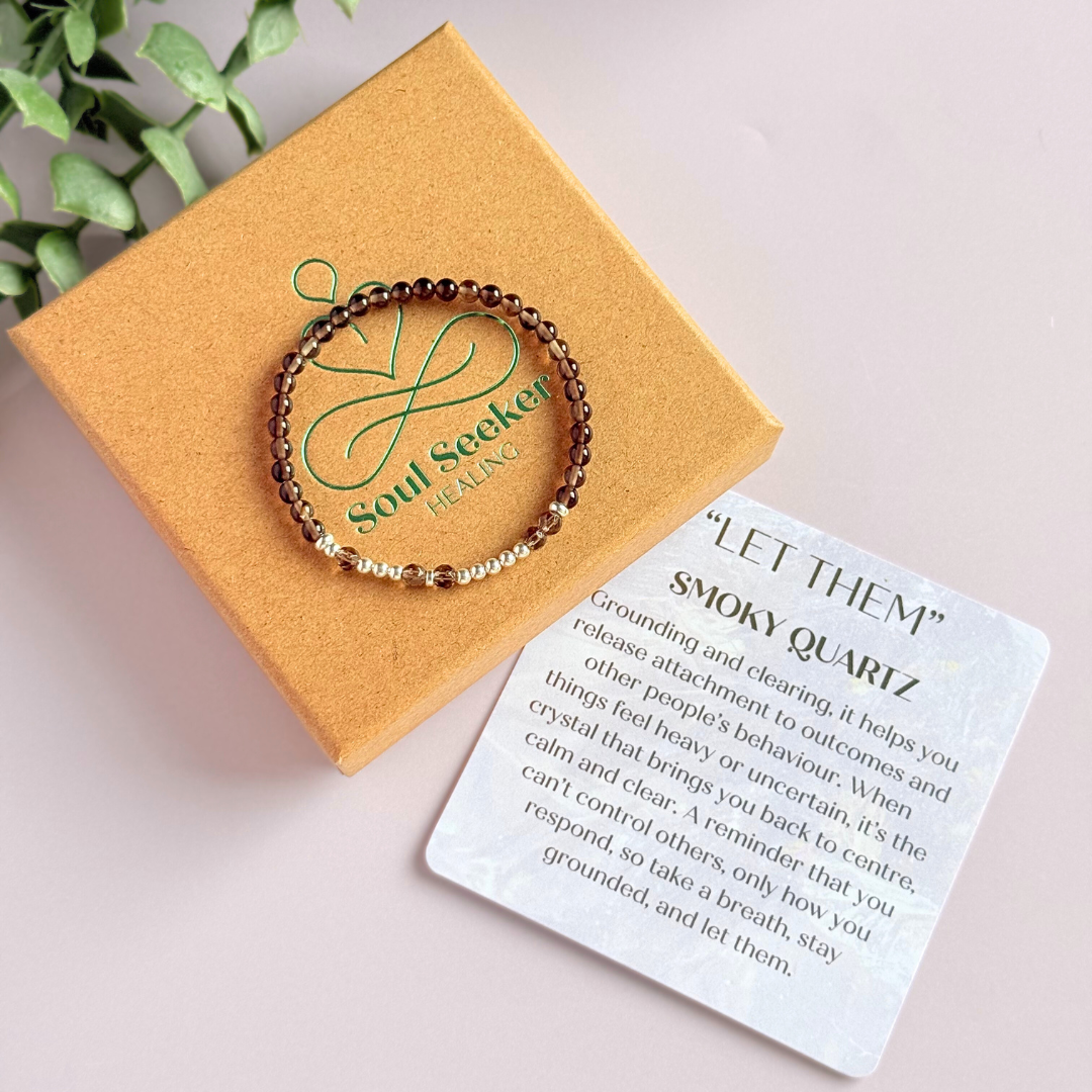 Elasticated smoky quartz crystal morse code bracelet that spells out the words ‘Let them’ in a combination of 4mm round smoky quartz beads, 4mm faceted smoky quartz beads and either sterling silver or gold vermeil 3mm round beads. The words start and end at the rondelle spacer beads.