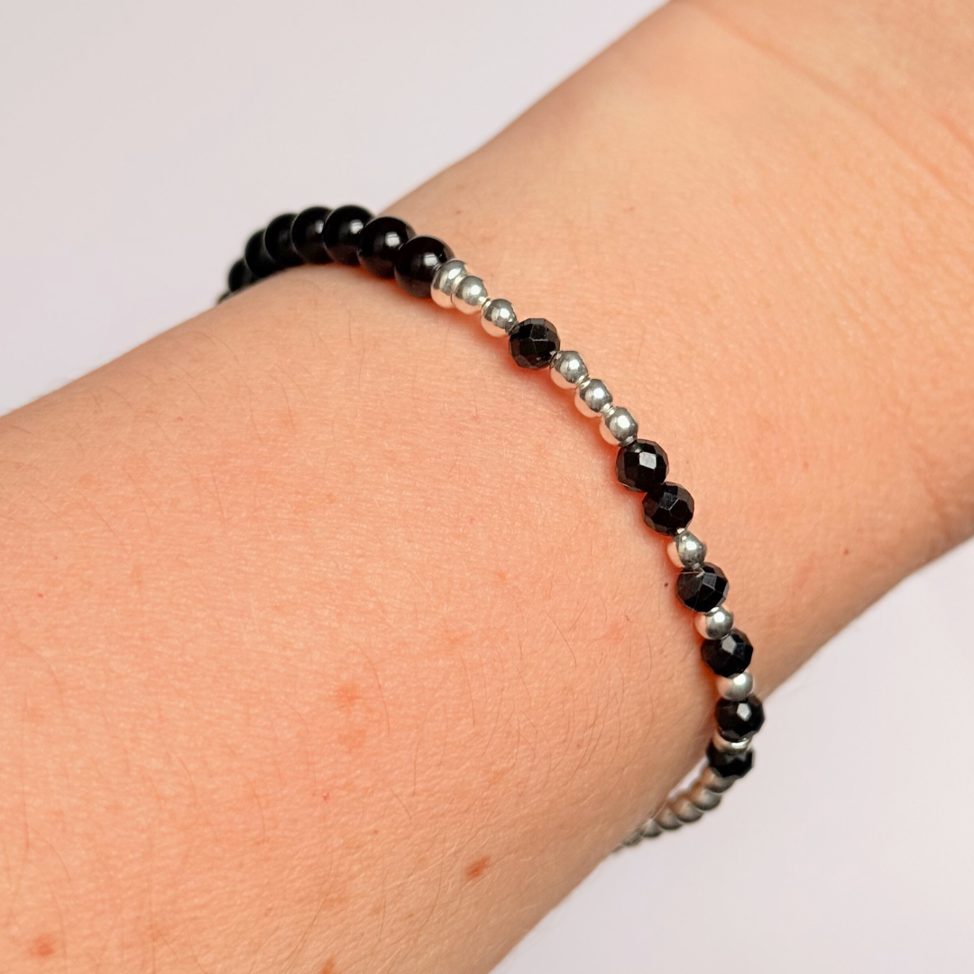 Elasticated black tourmaline crystal morse code bracelet spells out the words ‘Fuck this shit’ in a combination of 4mm round black tourmaline beads, 4mm faceted black tourmaline beads and either sterling silver or gold vermeil 3mm round beads. The words start and end at the rondelle spacer beads.