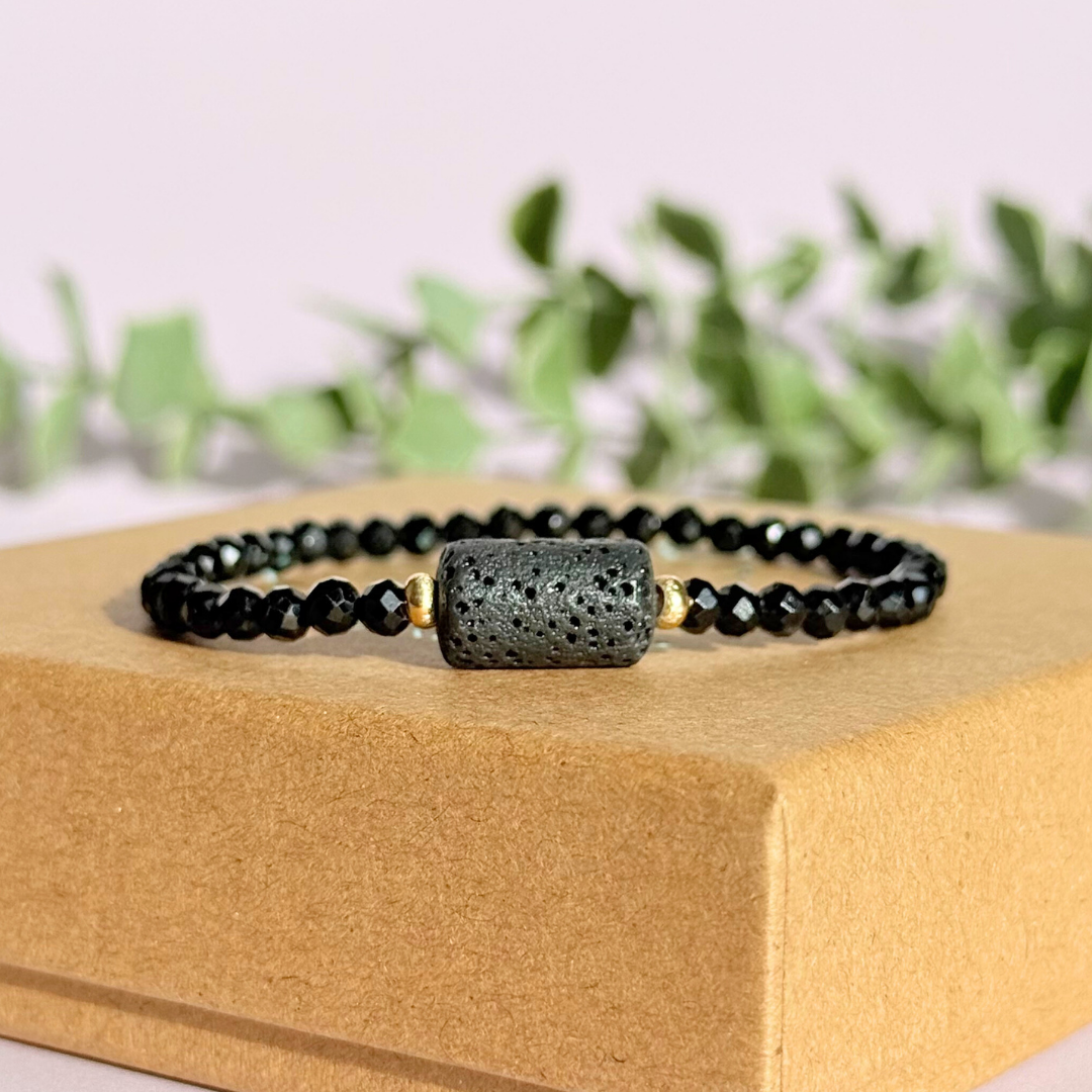 Essential oil diffuser bracelet featuring black lava rock tube bead on the band of 4mm faceted black tourmaline beads. Finished with your choice of sterling silver or gold vermeil accent beads.