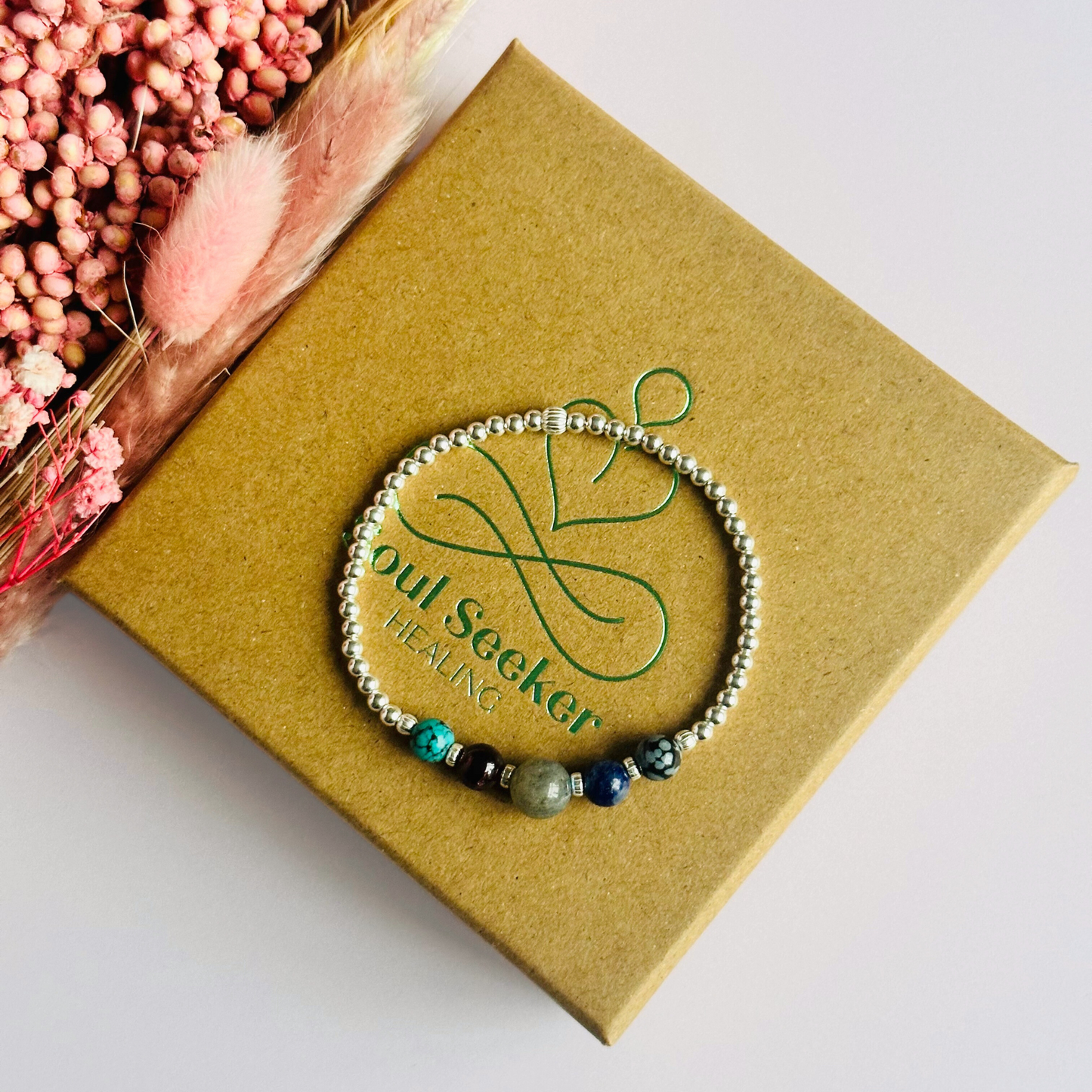 This sterling silver Sagittarius bracelet is made with a selection of five healing crystals all believed to resonate with the Sagittarius zodiac sign. The central bead is 8mm, the other four are 6mm. On an elasticated band of 3mm sterling silver beads with corrugated accent beads. Featuring garnet, labradorite, lapis lazuli, snowflake obsidian and turquoise.