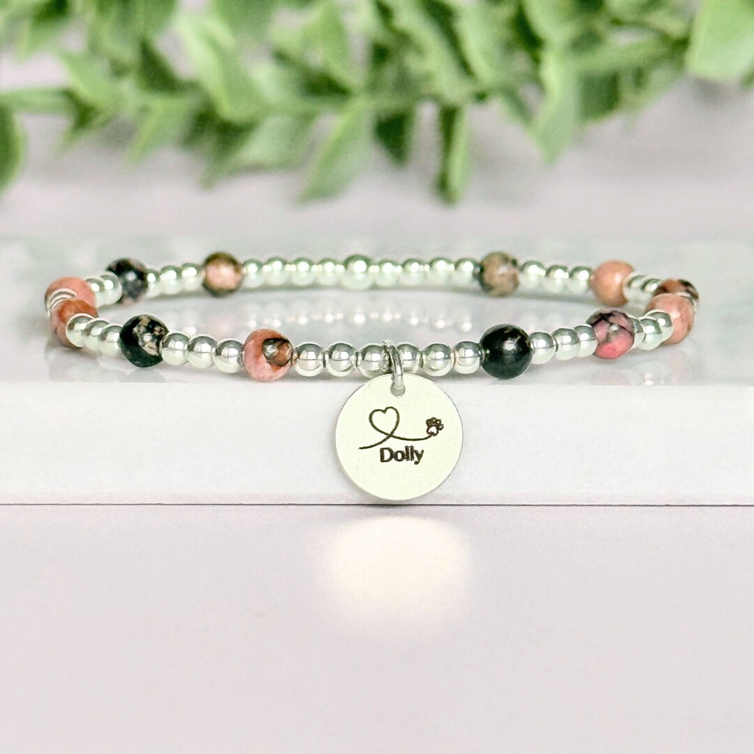 Sterling silver bracelet featuring ethically mined 4mm rhodonite crystal beads, separated by 3mm sterling silver beads. It features an 11mm sterling silver disc charm, which is engraved with a love heart and paw design, which can be personalised with your pet's name. The reverse of the charm says 'Forever in your heart x', although this side can also be personalised with your own words.