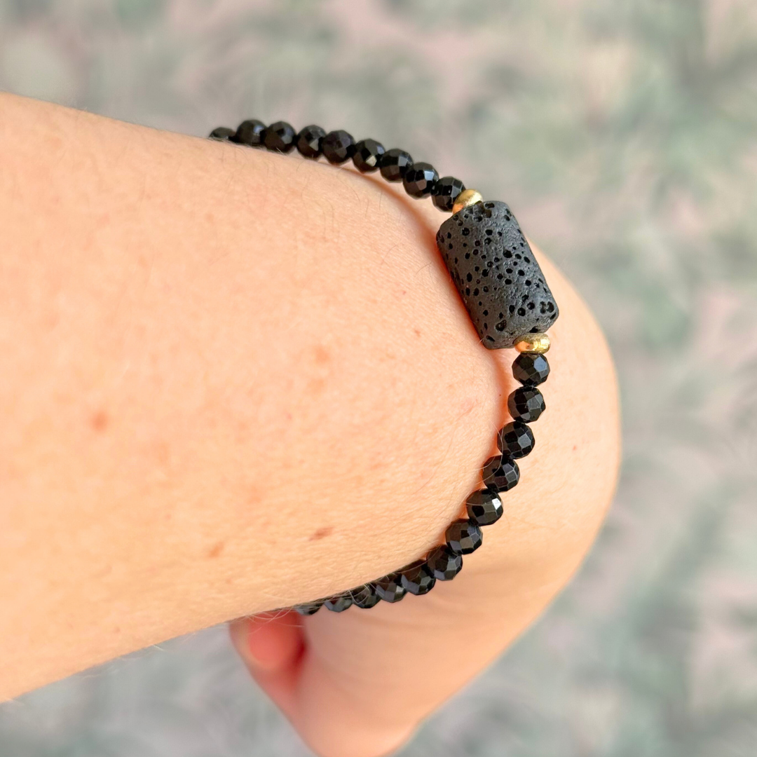 Essential oil diffuser bracelet featuring black lava rock tube bead on the band of 4mm faceted black tourmaline beads. Finished with your choice of sterling silver or gold vermeil accent beads.