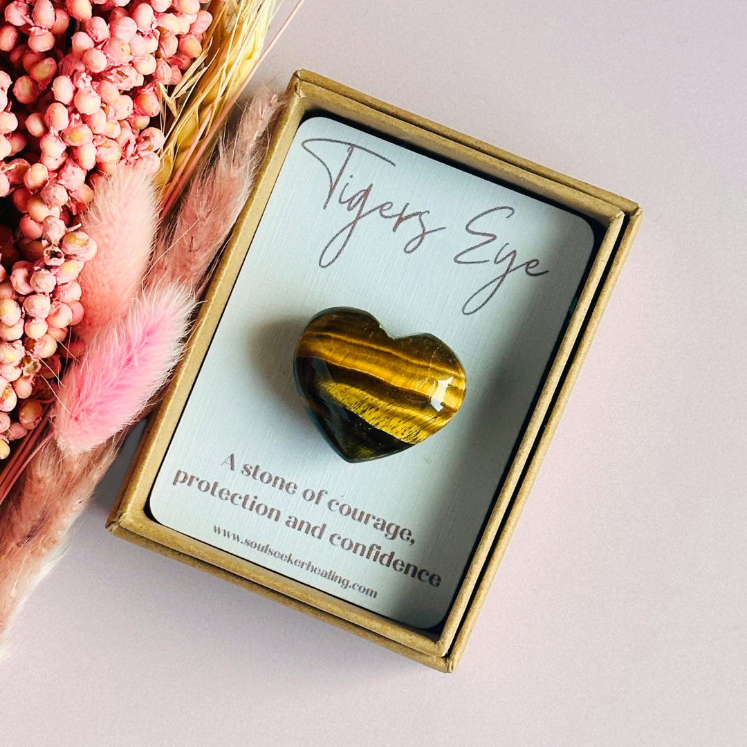 An ethically mined tigers eye heart, presented on an eco-friendly textured card with the words 'A stone of courage, protection and confidence. This heart shaped tigers eye crystal measures approximately 25mm x 25mm, making it an ideal size to carry with you wherever you go or to display in your sacred space. A cotton bag is included to keep it safe.