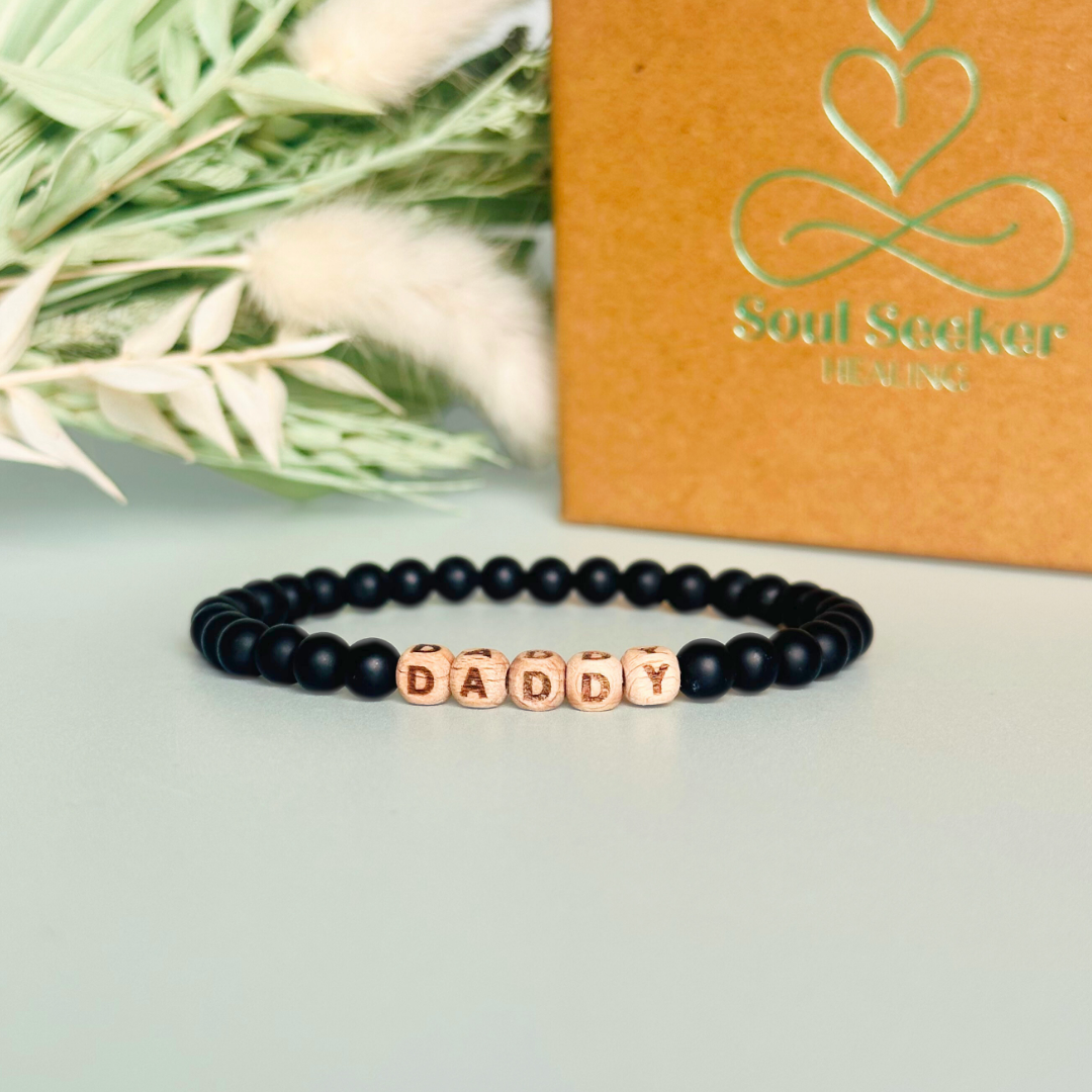 Men’s crystal bracelet with 6mm frosted black onyx gemstone crystal beads and laser engraved wooden letter beads featuring the word daddy or can also be made with any other words or letters.