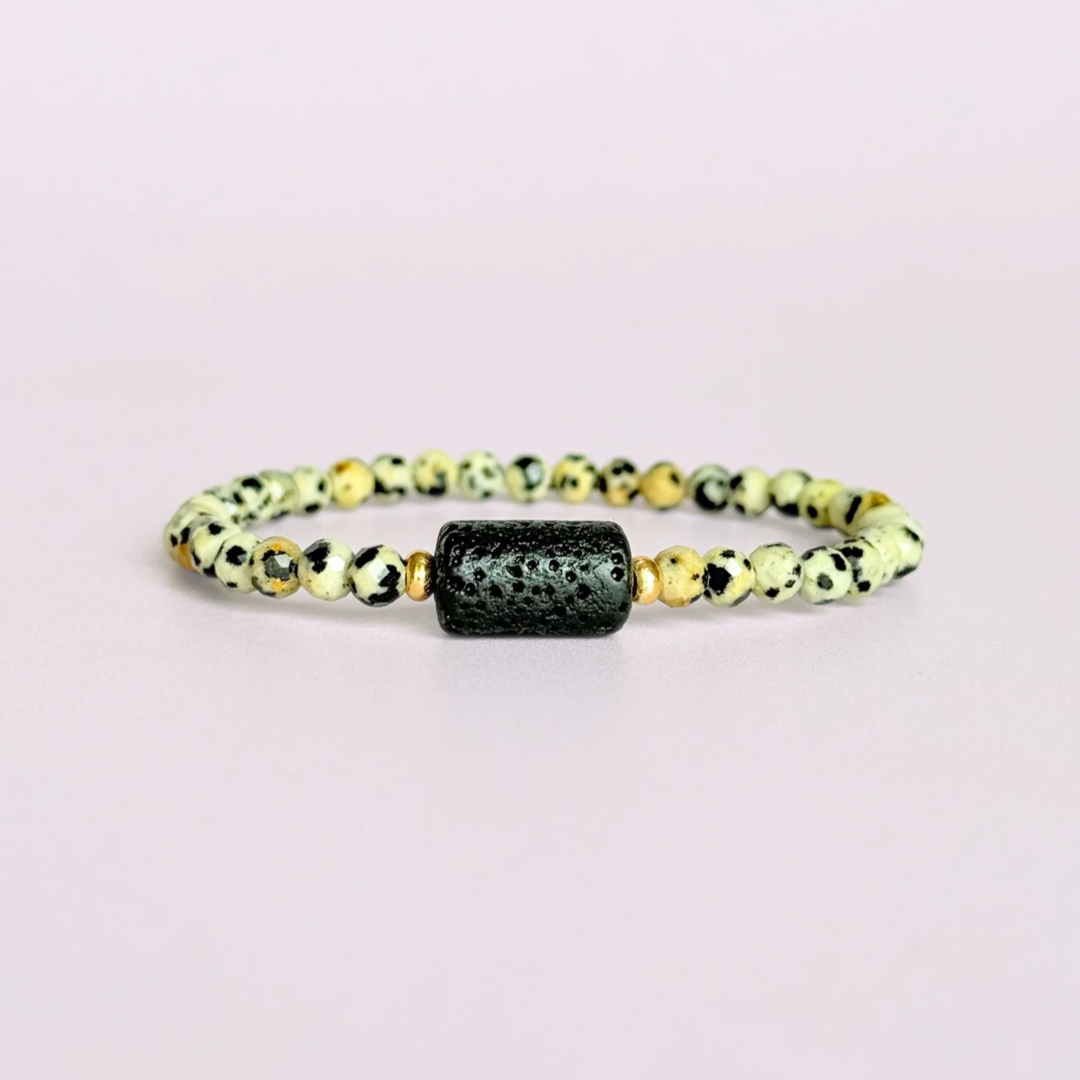 Essential oil diffuser bracelet featuring black lava rock tube bead on the band of 4mm faceted dalmatian jasper beads. Finished with your choice of sterling silver or gold vermeil accent beads.