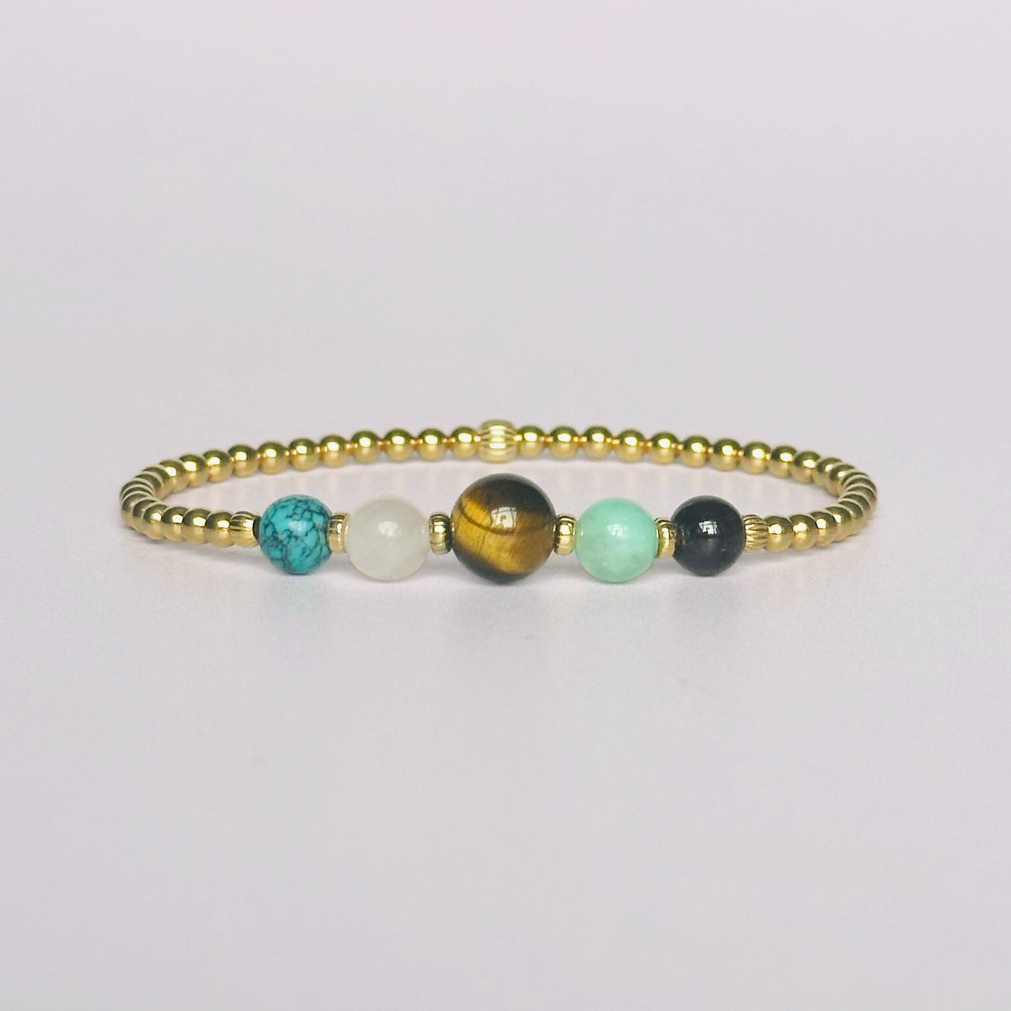 This gold vermeil Leo bracelet is made with a selection of five healing crystals all believed to resonate with the Leo zodiac sign. The central bead is 8mm, the other four are 6mm. On an elasticated band of 3mm gold vermeil beads with corrugated accent beads. Featuring chrysocolla, garnet, tigers eye, rose quartz and turquoise.