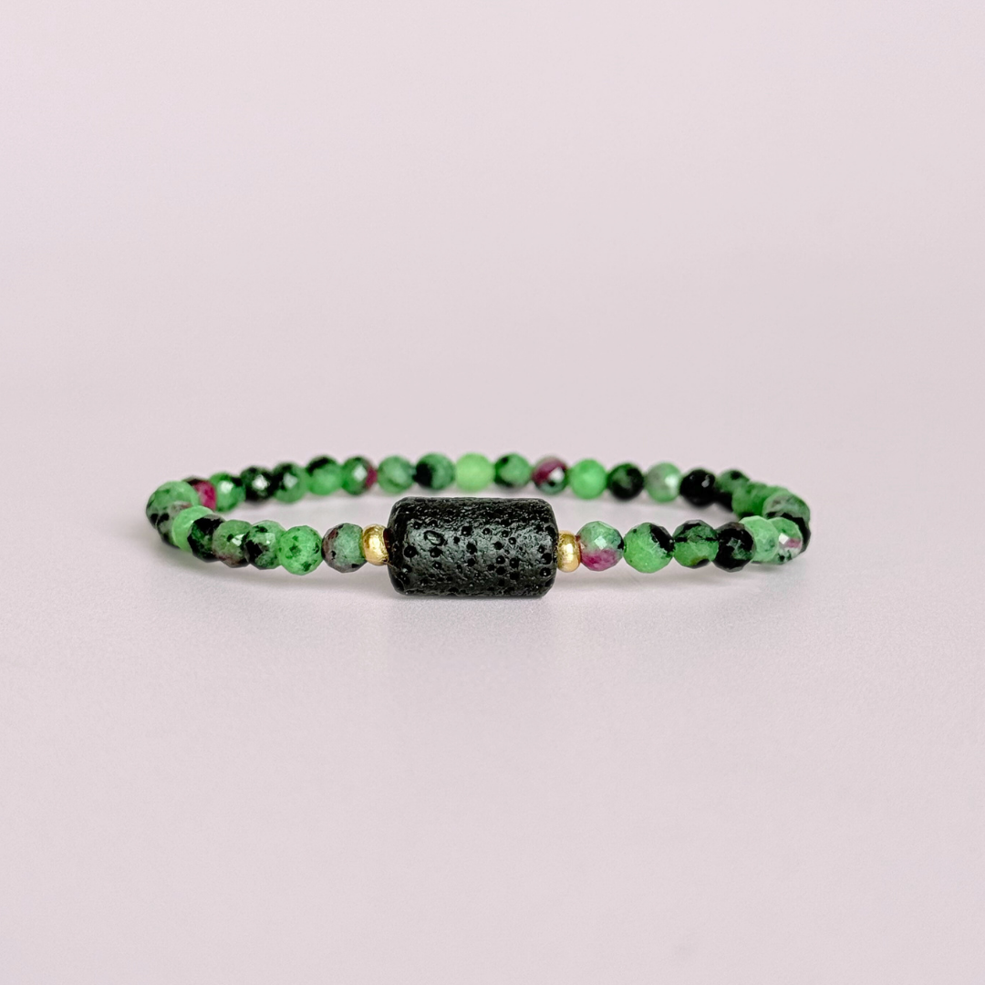Essential oil diffuser bracelet featuring black lava rock tube bead on the band of 4mm faceted ruby in zoisite beads. Finished with your choice of sterling silver or gold vermeil accent beads.