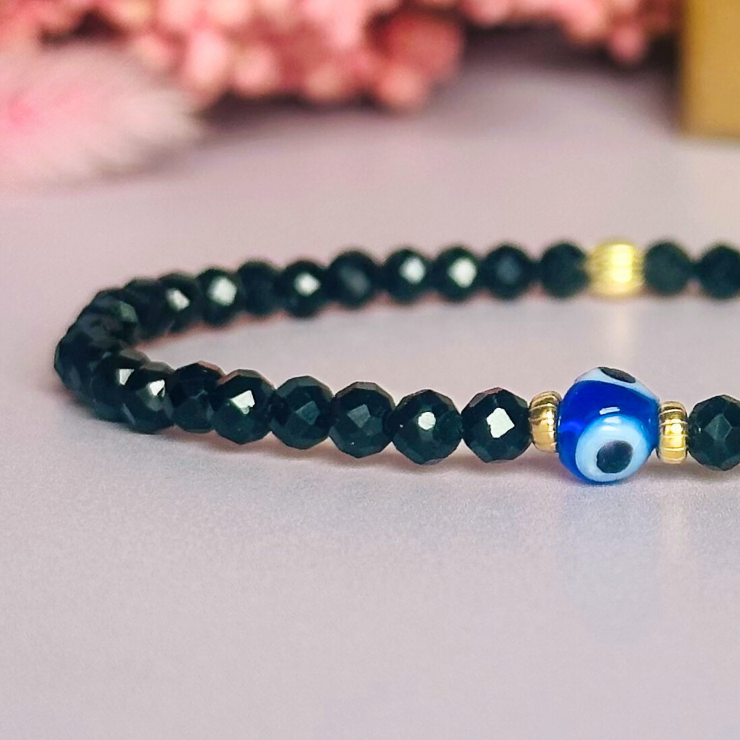 Dainty natural black tourmaline bracelet featuring ethically mined 4mm faceted gemstone beads, with a beautiful Turkish evil eye glass bead as the focal point. Choose from sterling silver or gold vermeil accent beads.