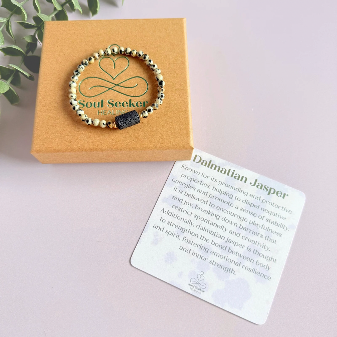 Essential oil diffuser bracelet featuring black lava rock tube bead on the band of 4mm faceted dalmatian jasper beads. Finished with your choice of sterling silver or gold vermeil accent beads.