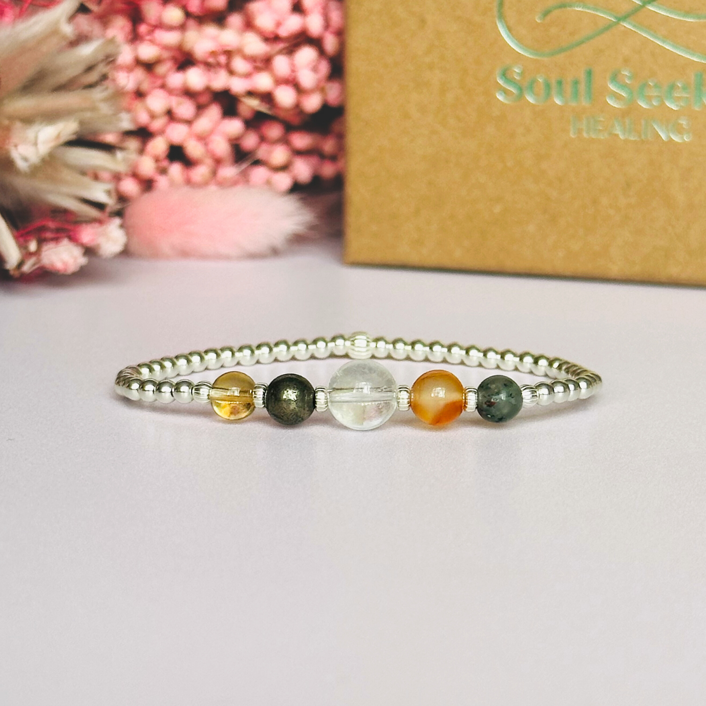 This sterling silver Aries bracelet is made with a selection of five healing crystals all believed to resonate with the Aries zodiac sign. The central bead is 8mm, the other four are 6mm. On an elasticated band of 3mm sterling silver beads with corrugated accent beads. Featuring carnelian, bloodstone, pyrite, clear quartz and citrine.