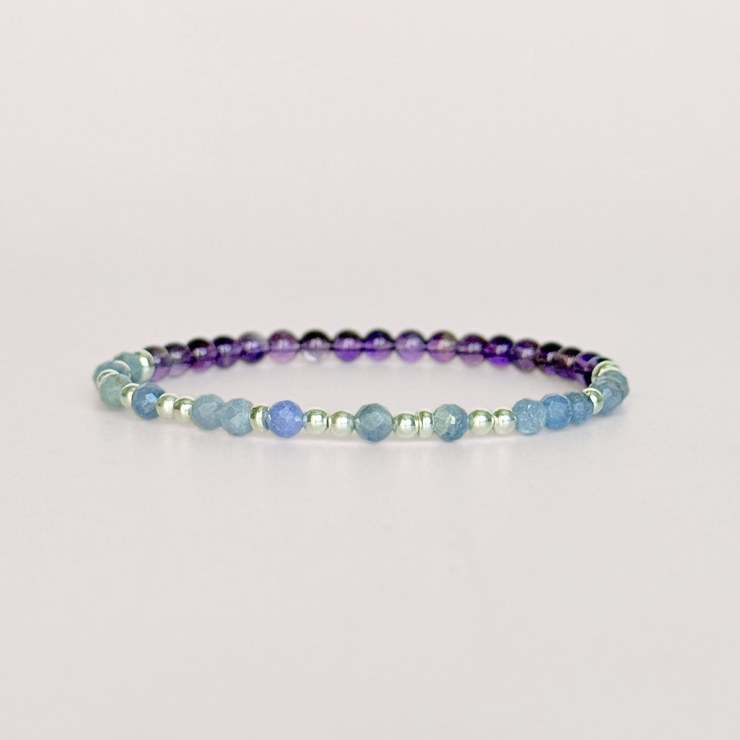 Amethyst and tanzanite elasticated stretch crystal morse code bracelet that spells out the words ‘Calm TF down’ in a combination of 4mm round amethyst beads, 4mm faceted tanzanite beads and either sterling silver or gold vermeil 3mm round beads. The words start and end at the rondelle spacer beads.