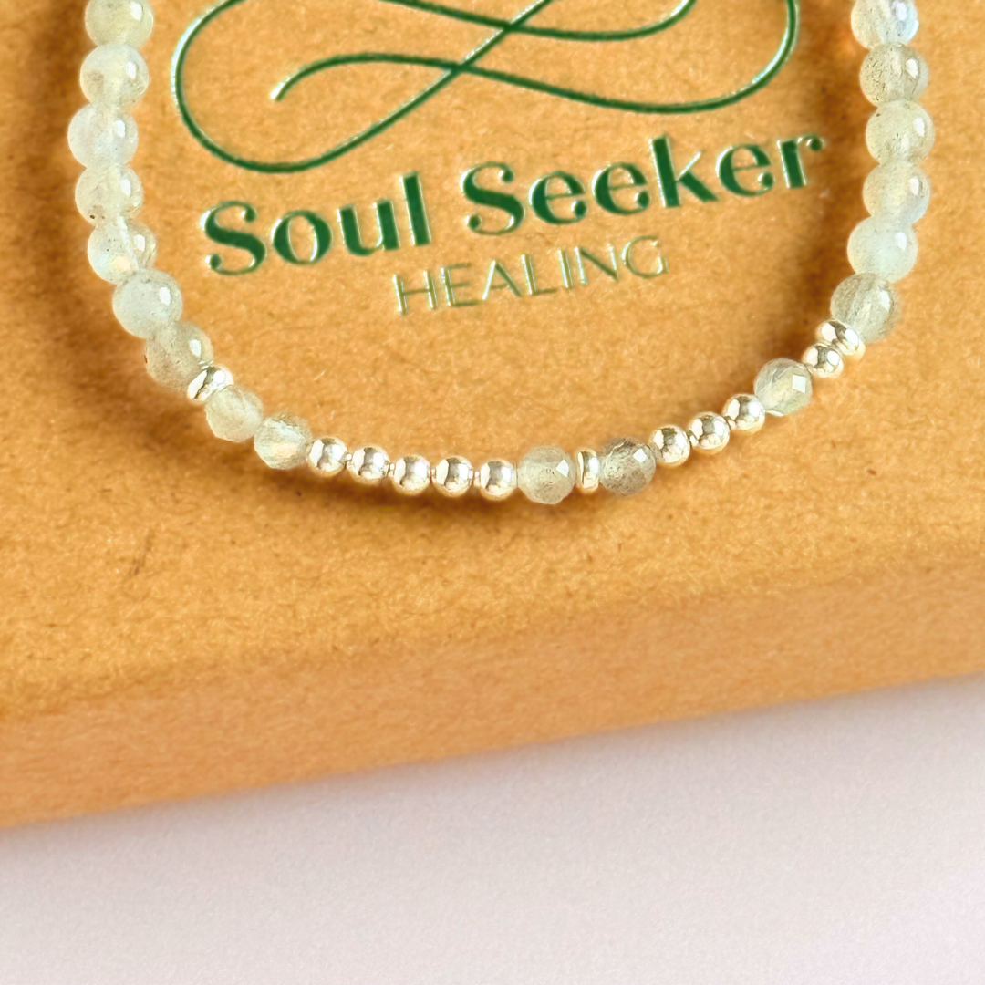 Elasticated labradorite crystal morse code bracelet that spells out the words ‘Let them’ in a combination of 4mm round labradorite beads, 4mm faceted labradorite beads and either sterling silver or gold vermeil 3mm round beads. The words start and end at the rondelle spacer beads.
