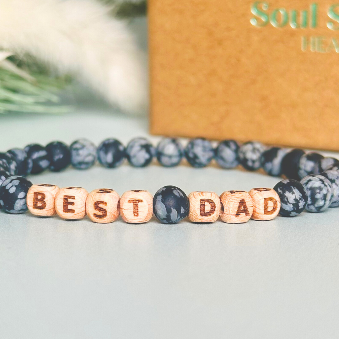 Men’s crystal bracelet with 6mm frosted snowflake obsidian gemstone crystal beads and laser engraved wooden letter beads featuring the word best dad or can also be made with any other words or letters.
