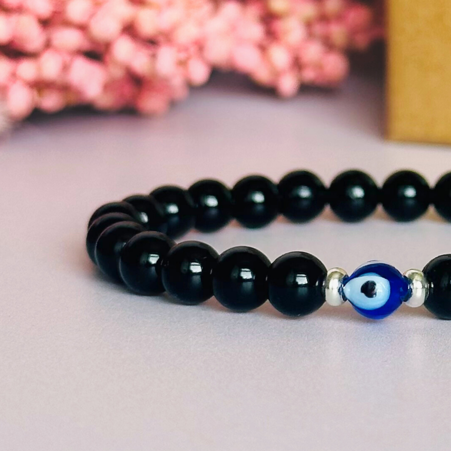 Natural black tourmaline bracelet featuring ethically mined smooth 6mm round beads with a beautiful blue Turkish evil eye glass bead as the focal point. Finished with gold vermeil or sterling silver accent beads.