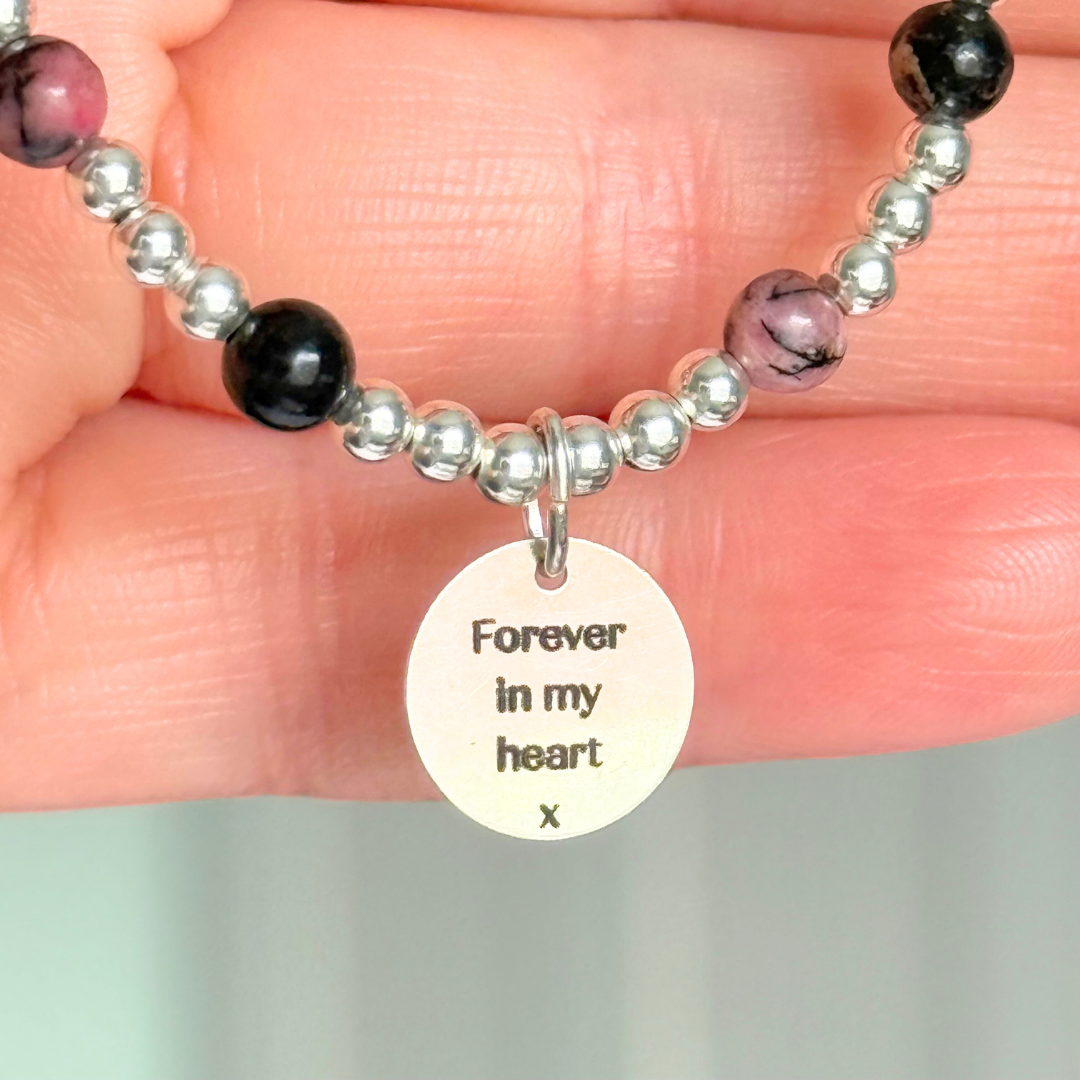 Sterling silver bracelet featuring ethically mined 4mm rhodonite crystal beads, separated by 3mm sterling silver beads. It features an 11mm sterling silver disc charm, which is engraved with a love heart and paw design, which can be personalised with your pet's name. The reverse of the charm says 'Forever in your heart x', although this side can also be personalised with your own words.