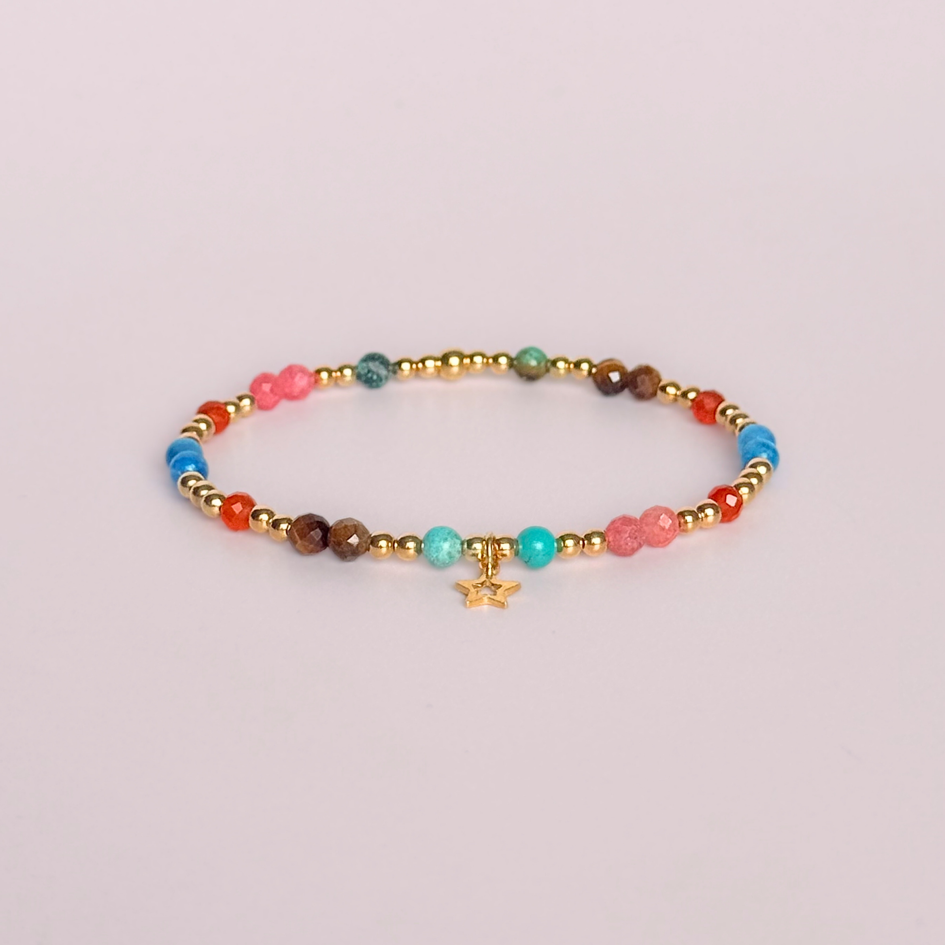 'Hot girl summer' gold vermeil dainty beaded bracelet with tigers eye, turquoise, apatite, carnelian and rhodochrosite. With a beautiful open star charm.Made with round 3mm gold vermeil beads and 4mm smooth and faceted round crystal gemstone beads. Pictured on a pink background.
