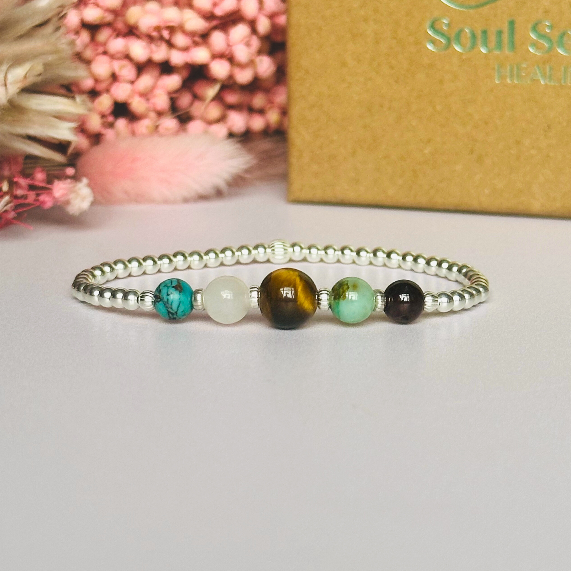 This sterling silver Leo bracelet is made with a selection of five healing crystals all believed to resonate with the Leo zodiac sign. The central bead is 8mm, the other four are 6mm. On an elasticated band of 3mm sterling silver beads with corrugated accent beads. Featuring chrysocolla, garnet, tigers eye, rose quartz and turquoise.