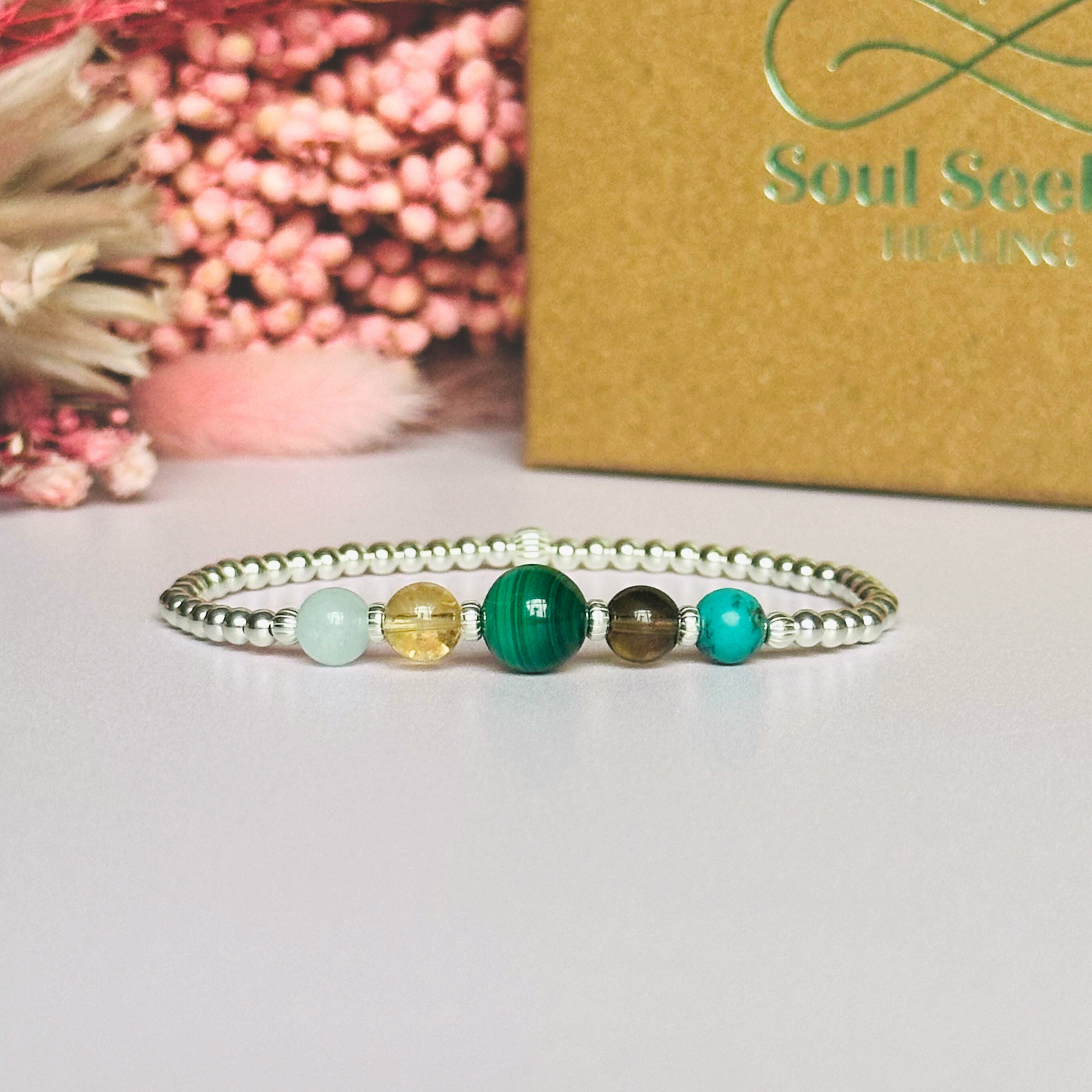 This sterling silver Scorpio bracelet is made with a selection of five healing crystals all believed to resonate with the Scorpio zodiac sign. The central bead is 8mm, the other four are 6mm. On an elasticated band of 3mm sterling silver beads with corrugated accent beads. Featuring aquamarine, citrine, malachite, smoky quartz and turquoise.