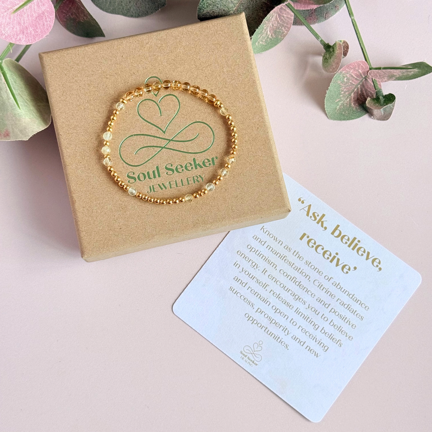 Citrine morse code bracelet that spells out the words ‘Ask, believe, receive’ in a combination of 4mm round smooth and faceted crystal beads with your choice of sterling silver or gold vermeil accent beads. Pictured in gold, on top of the gift box, with the crystal information card.