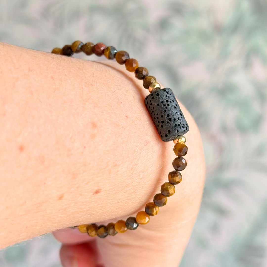 Essential oil diffuser bracelet featuring black lava rock tube bead on the band of 4mm faceted tigers eye beads. Finished with your choice of sterling silver or gold vermeil accent beads.