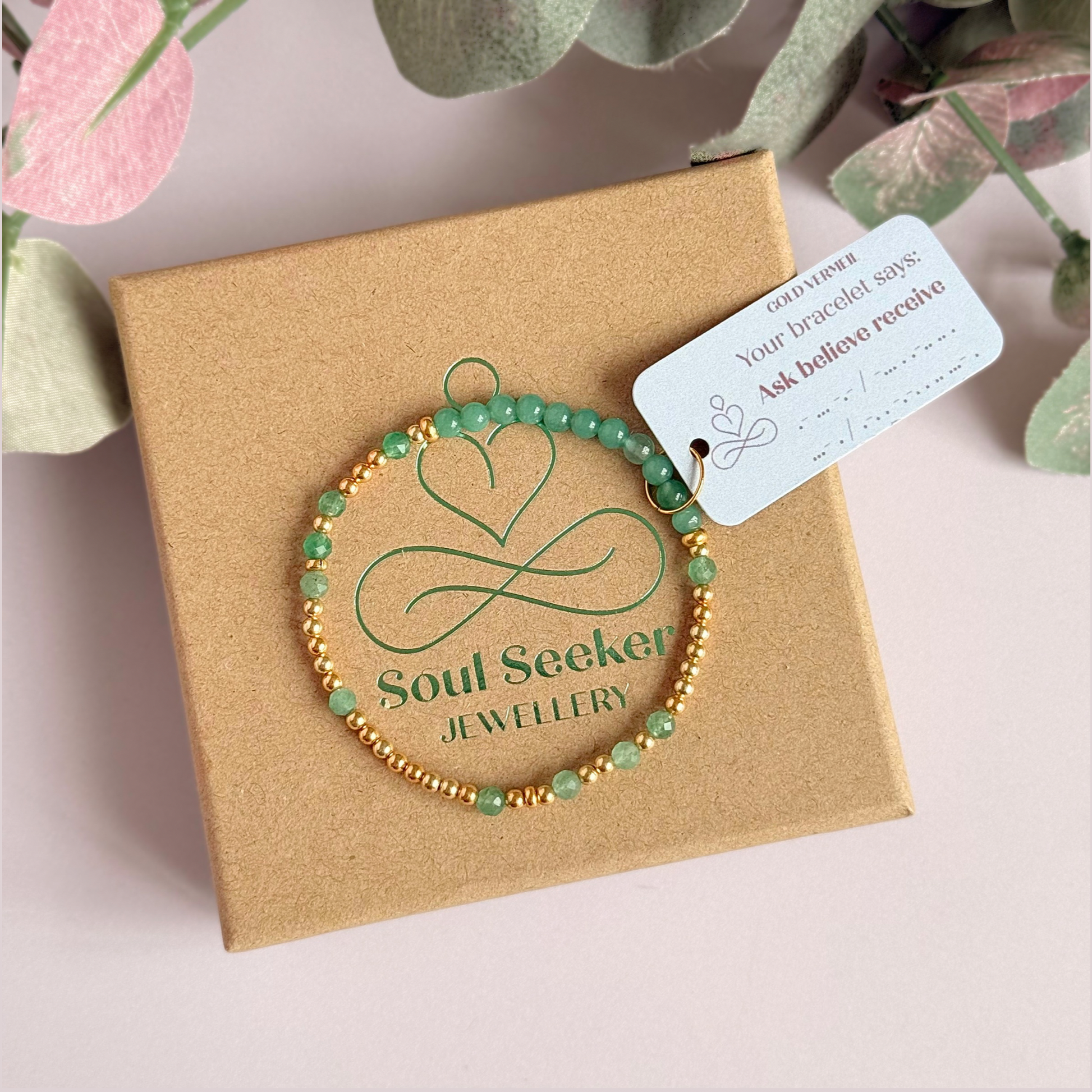 Green aventurine morse code bracelet that spells out the words ‘Ask, believe, receive’ in a combination of 4mm round smooth and faceted crystal beads with your choice of sterling silver or gold vermeil accent beads. Pictured in gold, on the gift box