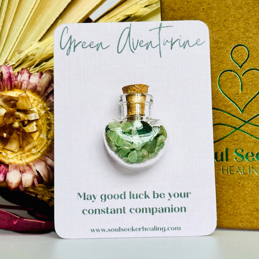 A pretty heart shaped mini glass bottle filled with powerful, ethically mined green aventurine crystal chips, known for their properties regarding good luck, abundance and success. Presented on a card with the words ‘may good luck be your constant companion.’ This bottle measures approximately 28mm x 23mm, including cork when it is pushed in.