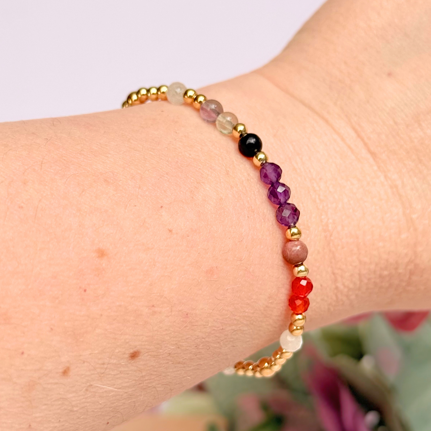 Dainty gold vermeil crystal bracelet featuring five crystals, in 4mm faceted and smooth round style, each believed to help with perimenopause symptoms. Featuring amethyst, rhodonite, fluorite, moonstone and carnelian. Pictured being worn.