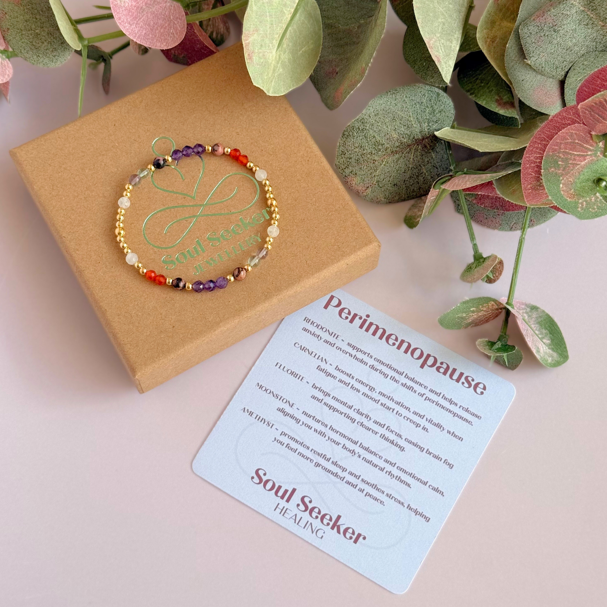 Dainty gold vermeil crystal bracelet featuring five crystals, in 4mm faceted and smooth round style, each believed to help with perimenopause symptoms. Featuring amethyst, rhodonite, fluorite, moonstone and carnelian. Pictured on top of the gift box, with the crystal information card.