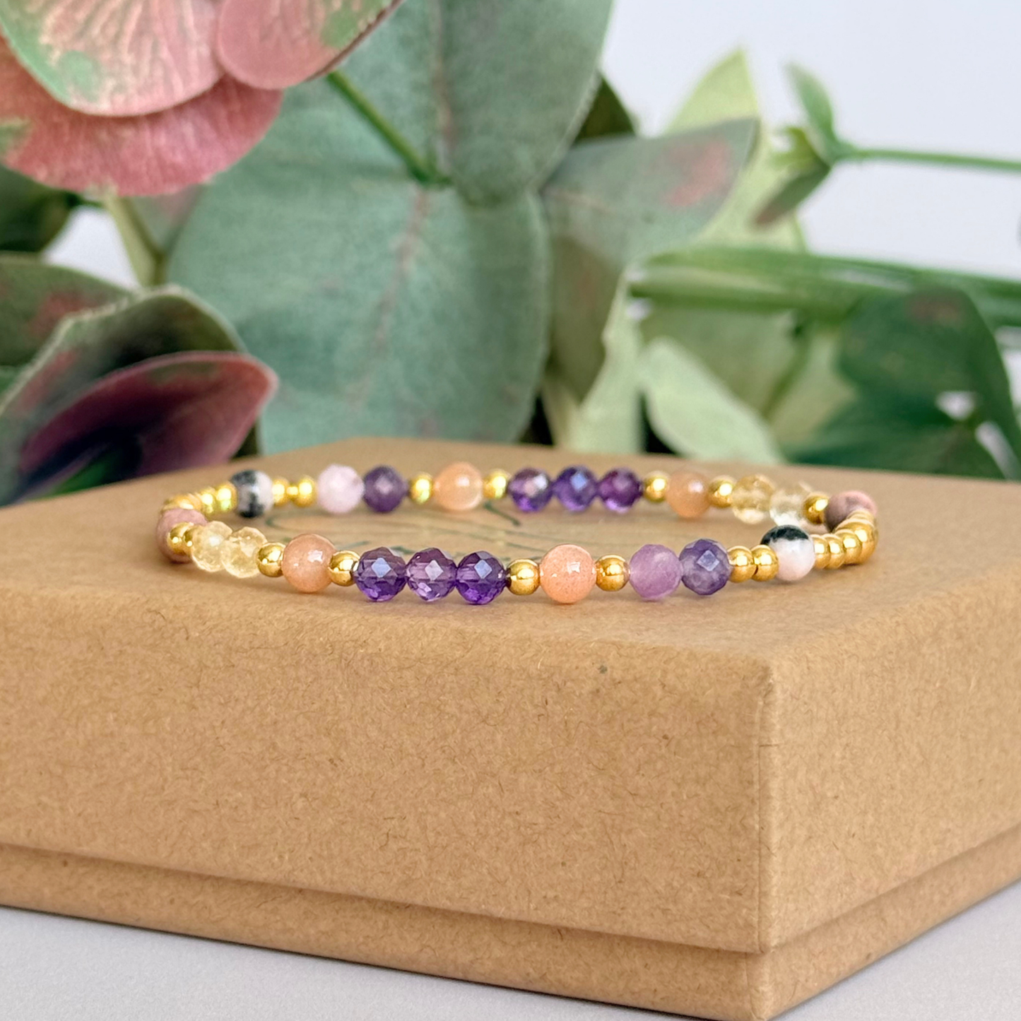 Dainty gold vermeil crystal bracelet featuring five crystals, in 4mm faceted and smooth round style, each believed to help with menopause symptoms. Featuring amethyst, citrine, lepidolite, peach moonstone and pink zebra jasper. Pictured on top of the gift box.