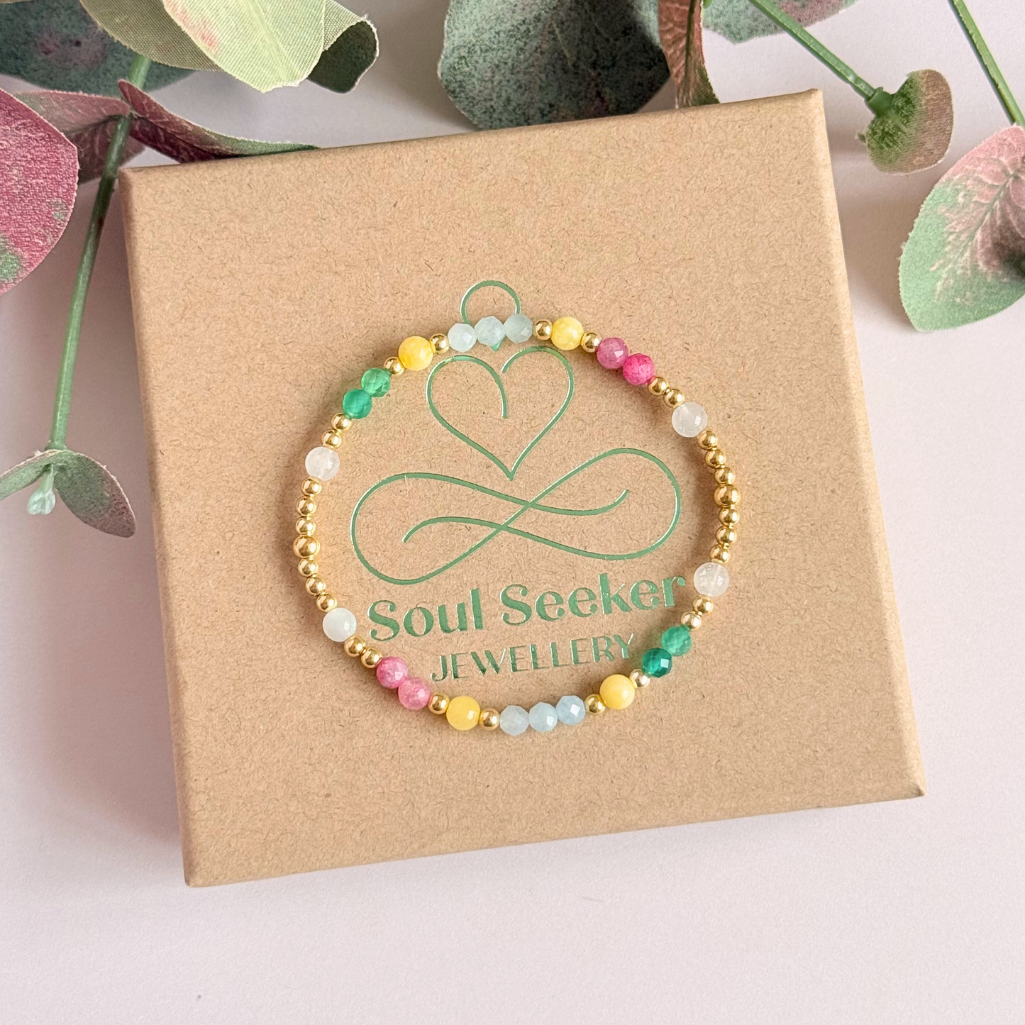 'Amalfi Coast' gold vermeil dainty beaded bracelet with green agate, yellow calcite, pink tourmaline, aquamarine and moonstone. Made with round 3mm gold vermeil beads and 4mm smooth and faceted round crystal gemstone beads. Pictured from above, on top of the gift box