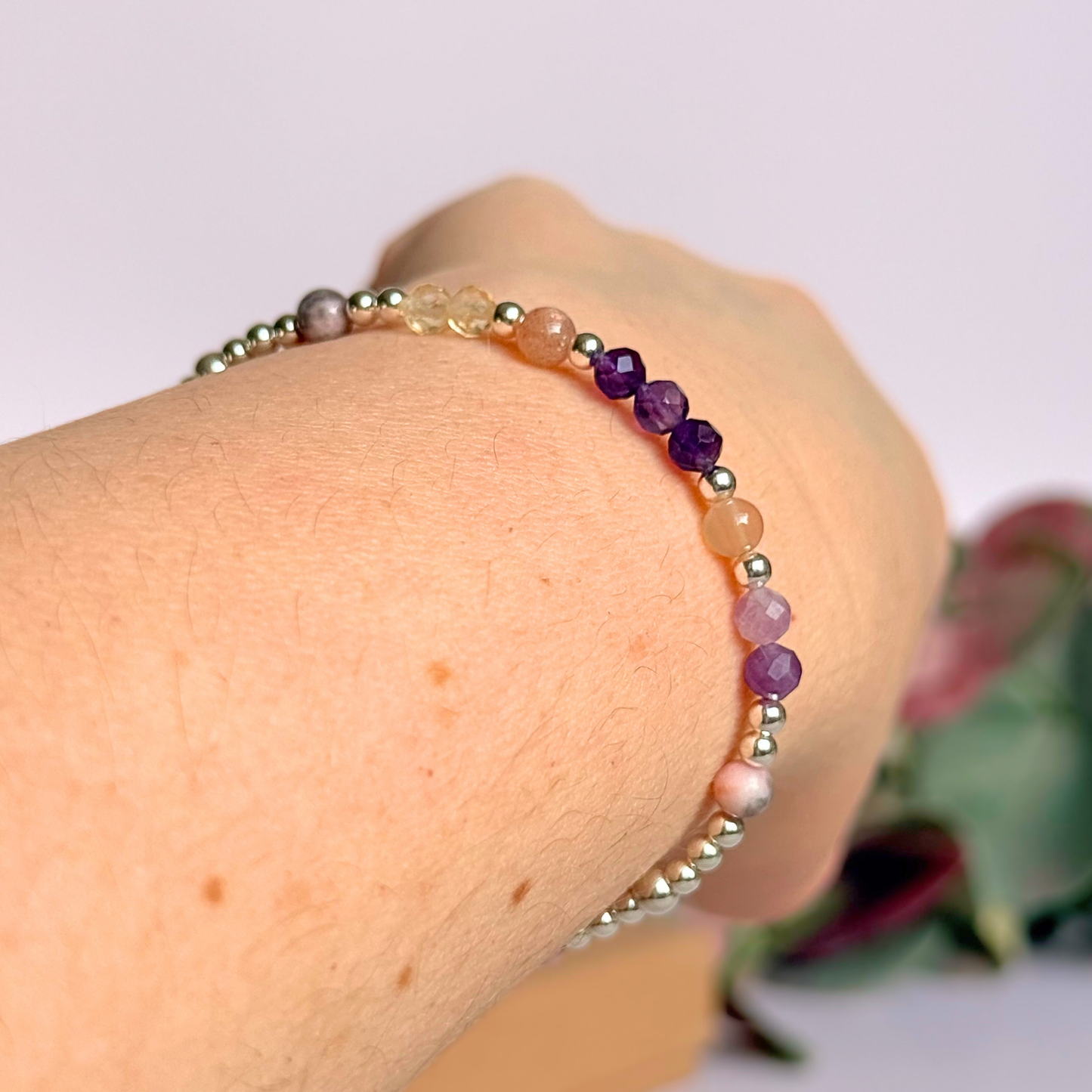 Dainty sterling silver crystal bracelet featuring five crystals, in 4mm faceted and smooth round style, each believed to help with menopause symptoms. Featuring amethyst, citrine, lepidolite, peach moonstone and pink zebra jasper. Pictured being worn, on an angle.