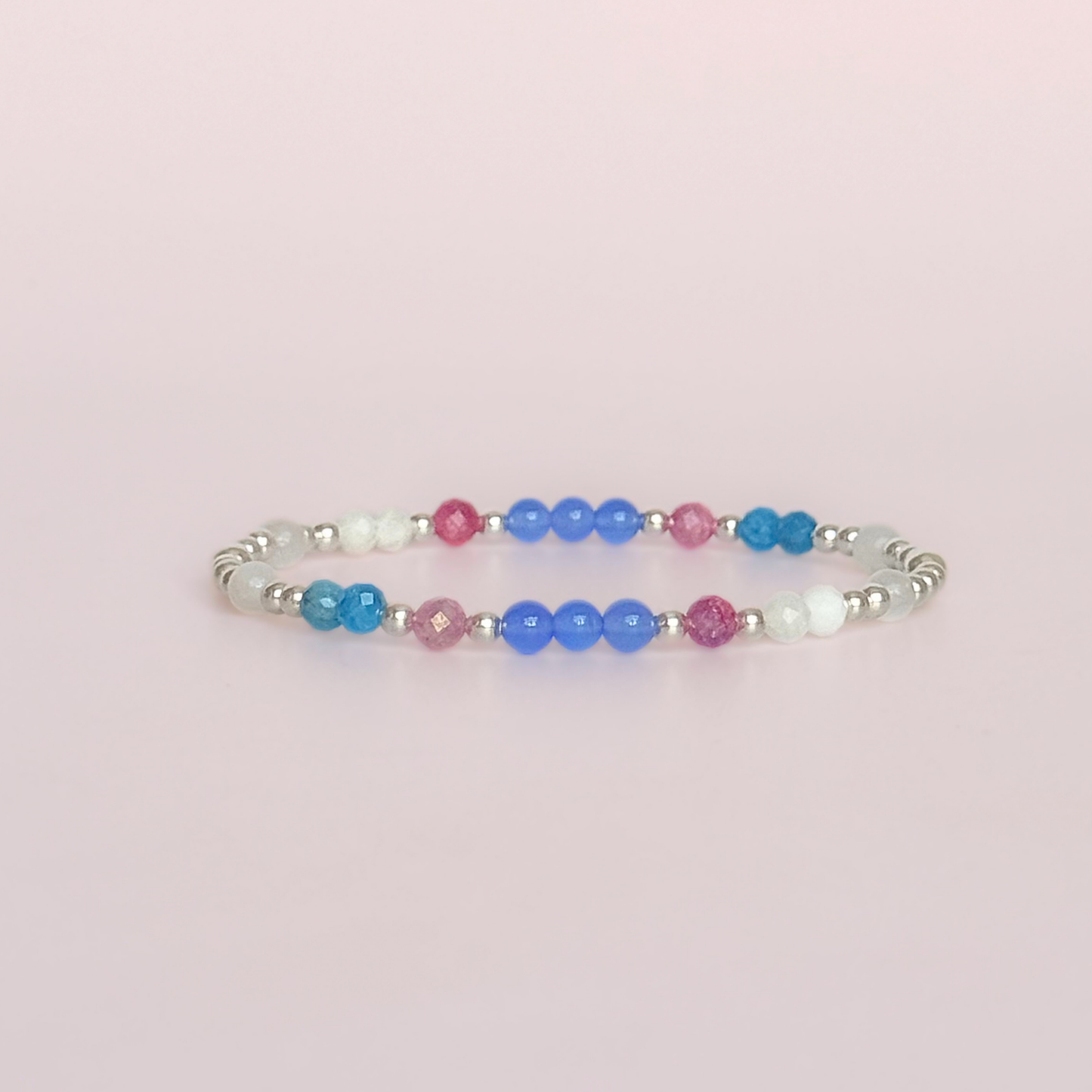 ‘Santorini' sterling silver dainty beaded bracelet with pink tourmaline, rainbow moonstone, blue agate, apatite and white jade. Made with round 3mm sterling silver beads and 4mm smooth and faceted round crystal gemstone beads. Pictured against a pink background