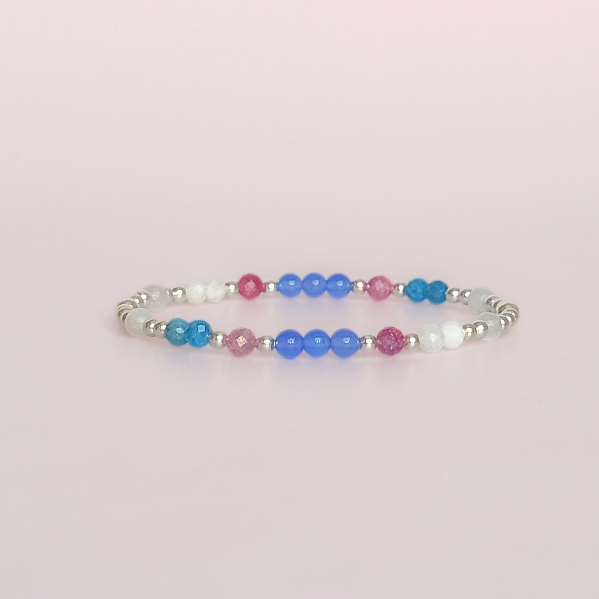 ‘Santorini' sterling silver dainty beaded bracelet with pink tourmaline, rainbow moonstone, blue agate, apatite and white jade. Made with round 3mm sterling silver beads and 4mm smooth and faceted round crystal gemstone beads. Pictured against a pink background