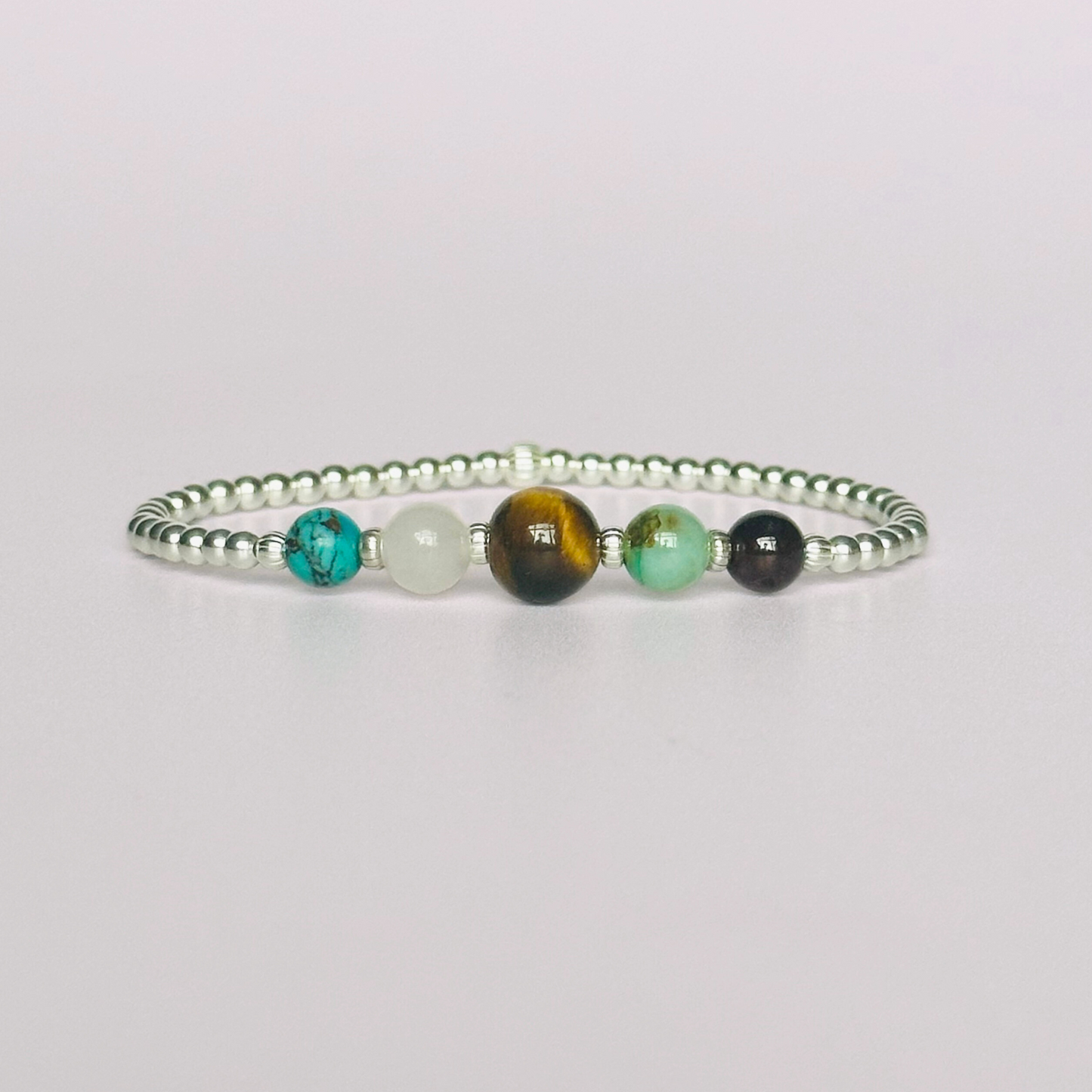 This sterling silver Leo bracelet is made with a selection of five healing crystals all believed to resonate with the Leo zodiac sign. The central bead is 8mm, the other four are 6mm. On an elasticated band of 3mm sterling silver beads with corrugated accent beads. Featuring chrysocolla, garnet, tigers eye, rose quartz and turquoise.