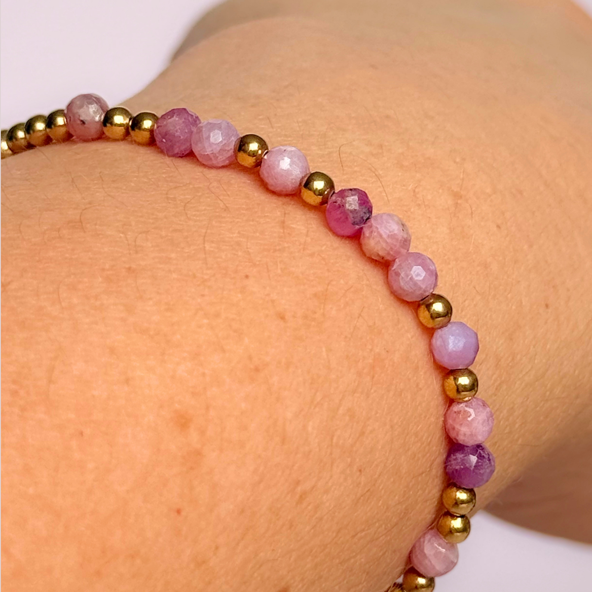 Dainty, minimalist gold vermeil and pink tourmaline October birthstone stacking bracelet. Made with 4mm faceted pink tourmaline beads and 3mm gold vermeil round beads. Elasticated for comfort. Pictured being worn, close up