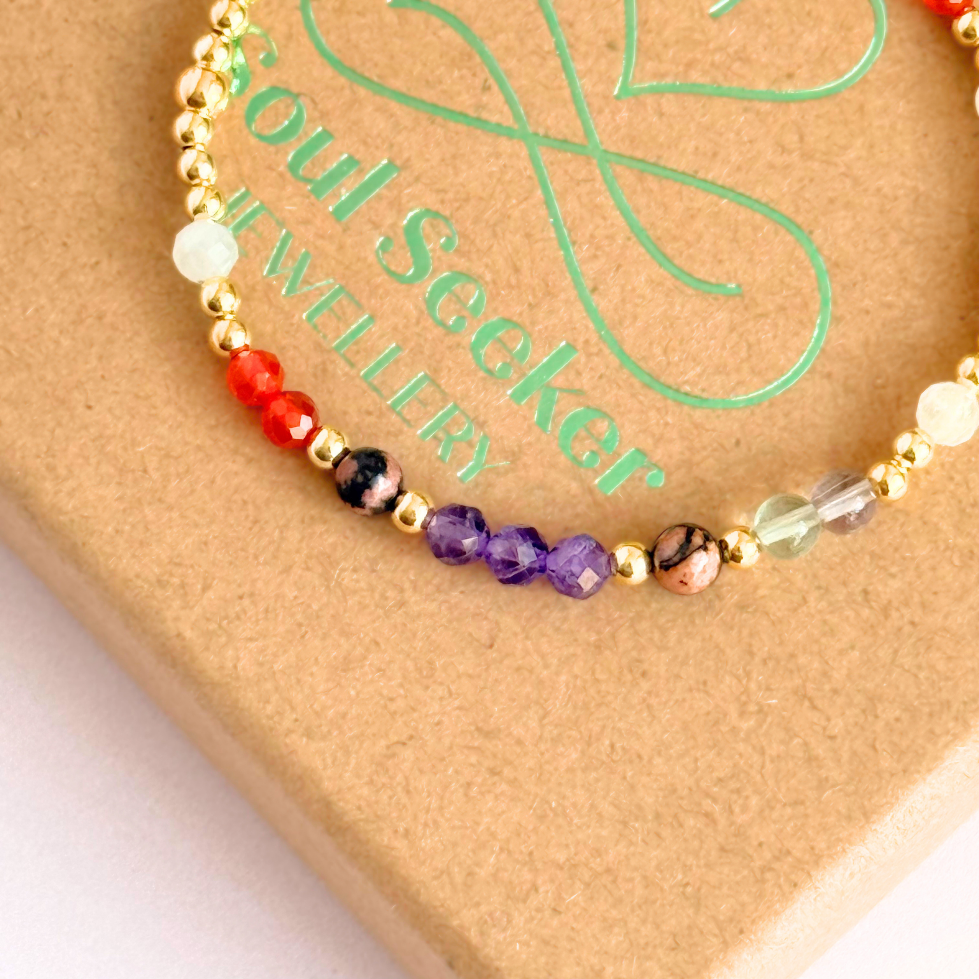 Dainty gold vermeil crystal bracelet featuring five crystals, in 4mm faceted and smooth round style, each believed to help with perimenopause symptoms. Featuring amethyst, rhodonite, fluorite, moonstone and carnelian. Pictured on top of the gift box, close up.