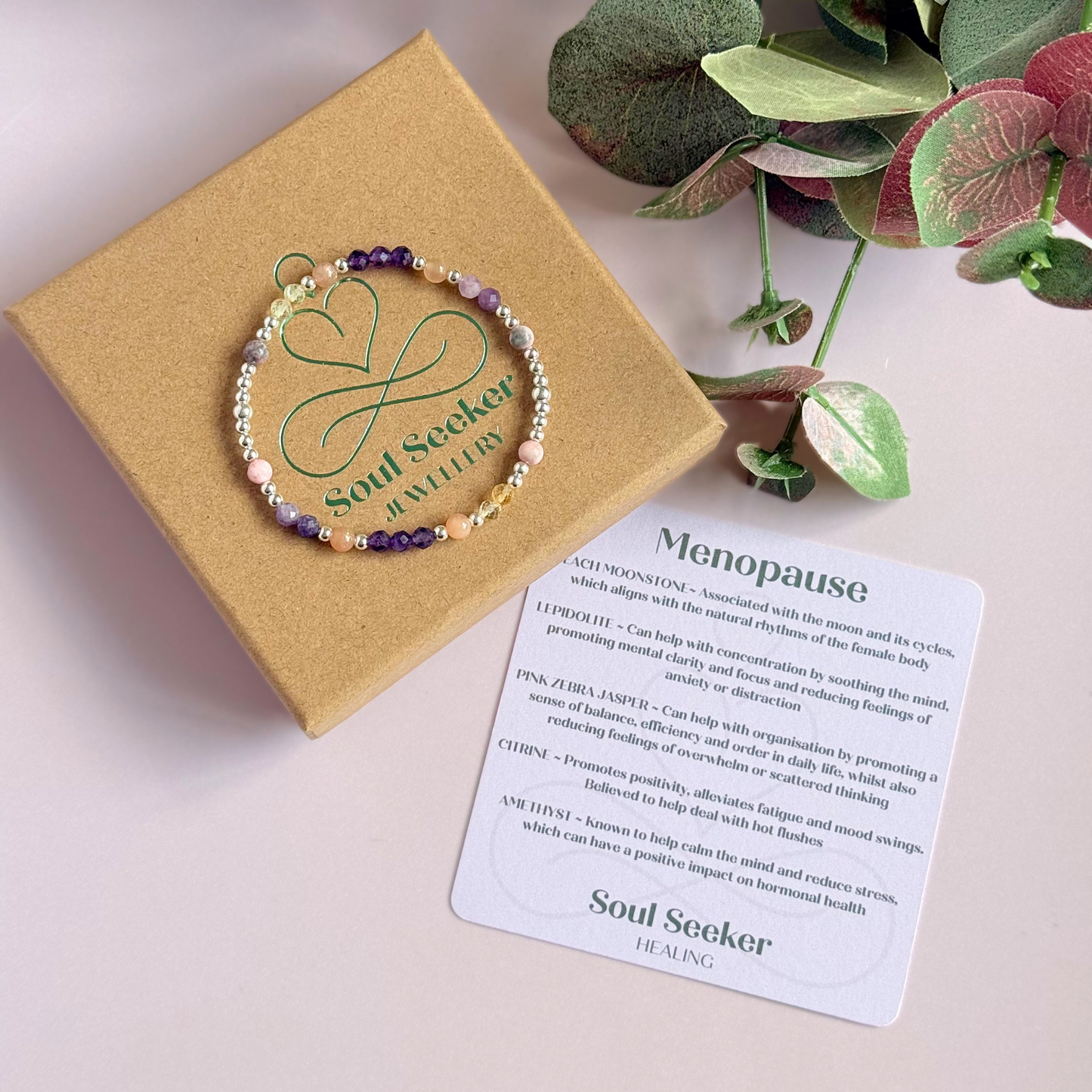 Dainty sterling silver crystal bracelet featuring five crystals, in 4mm faceted and smooth round style, each believed to help with menopause symptoms. Featuring amethyst, citrine, lepidolite, peach moonstone and pink zebra jasper. Pictured on top of the gift box with the crystal information card.