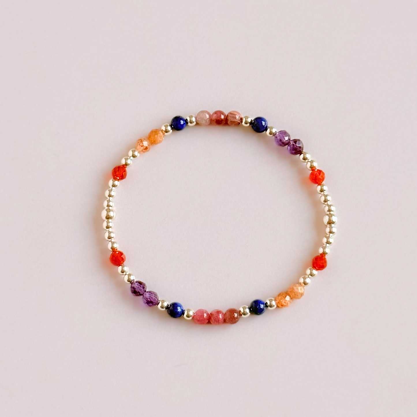 ‘Arabian Sunset' sterling silver dainty beaded bracelet with pink tourmaline, sunstone, carnelian, lapis lazuli and amethyst. Made with round 3mm sterling silver beads and 4mm smooth and faceted round crystal gemstone beads. Pictured from above, against a pink background