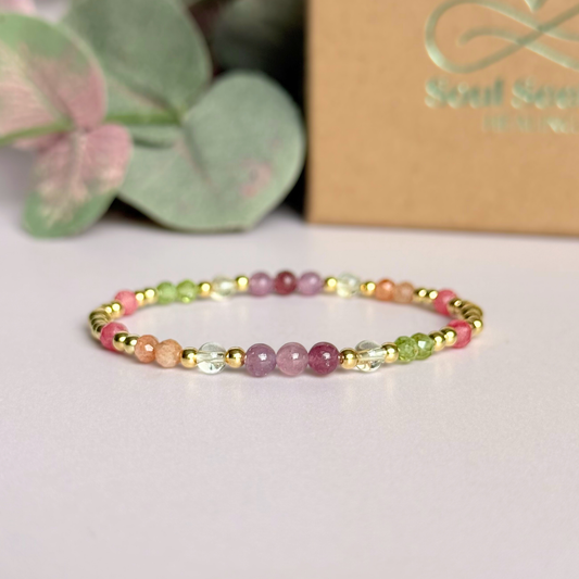 Dainty crystal bracelet featuring a carefully curated selection of genuine crystal beads inspired by wildflowers and free-spirited growth. Featuring 4mm smooth and faceted round gemstone beads with 3mm round accent beads in either sterling silver or gold vermeil. With peridot, sunstone, rhodochrosite, citrine and lepidolite. Picture features the bracelet in gold with the gift box in the background.