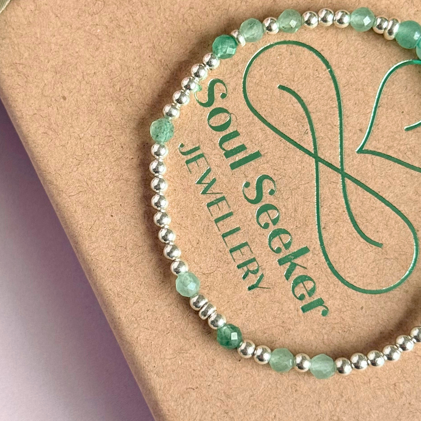 Green aventurine morse code bracelet that spells out the words ‘Ask, believe, receive’ in a combination of 4mm round smooth and faceted crystal beads with your choice of sterling silver or gold vermeil accent beads. Pictured in silver, close up on the gift box