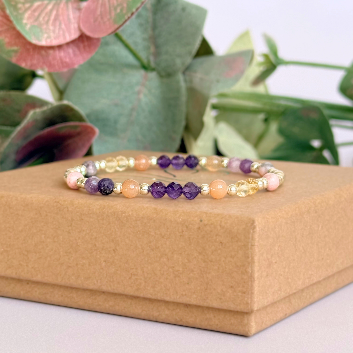 Dainty sterling silver crystal bracelet featuring five crystals, in 4mm faceted and smooth round style, each believed to help with menopause symptoms. Featuring amethyst, citrine, lepidolite, peach moonstone and pink zebra jasper. Pictured on top of the gift box.