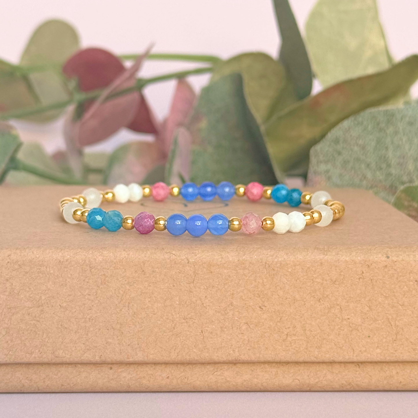 ‘Santorini' gold vermeil dainty beaded bracelet with pink tourmaline, rainbow moonstone, blue agate, apatite and white jade. Made with round 3mm gold vermeil beads and 4mm smooth and faceted round crystal gemstone beads. Pictured on the gift box, from the side
