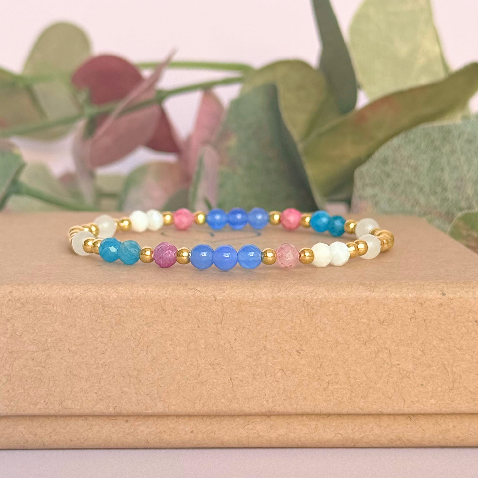 ‘Santorini' gold vermeil dainty beaded bracelet with pink tourmaline, rainbow moonstone, blue agate, apatite and white jade. Made with round 3mm gold vermeil beads and 4mm smooth and faceted round crystal gemstone beads. Pictured on the gift box, from the side
