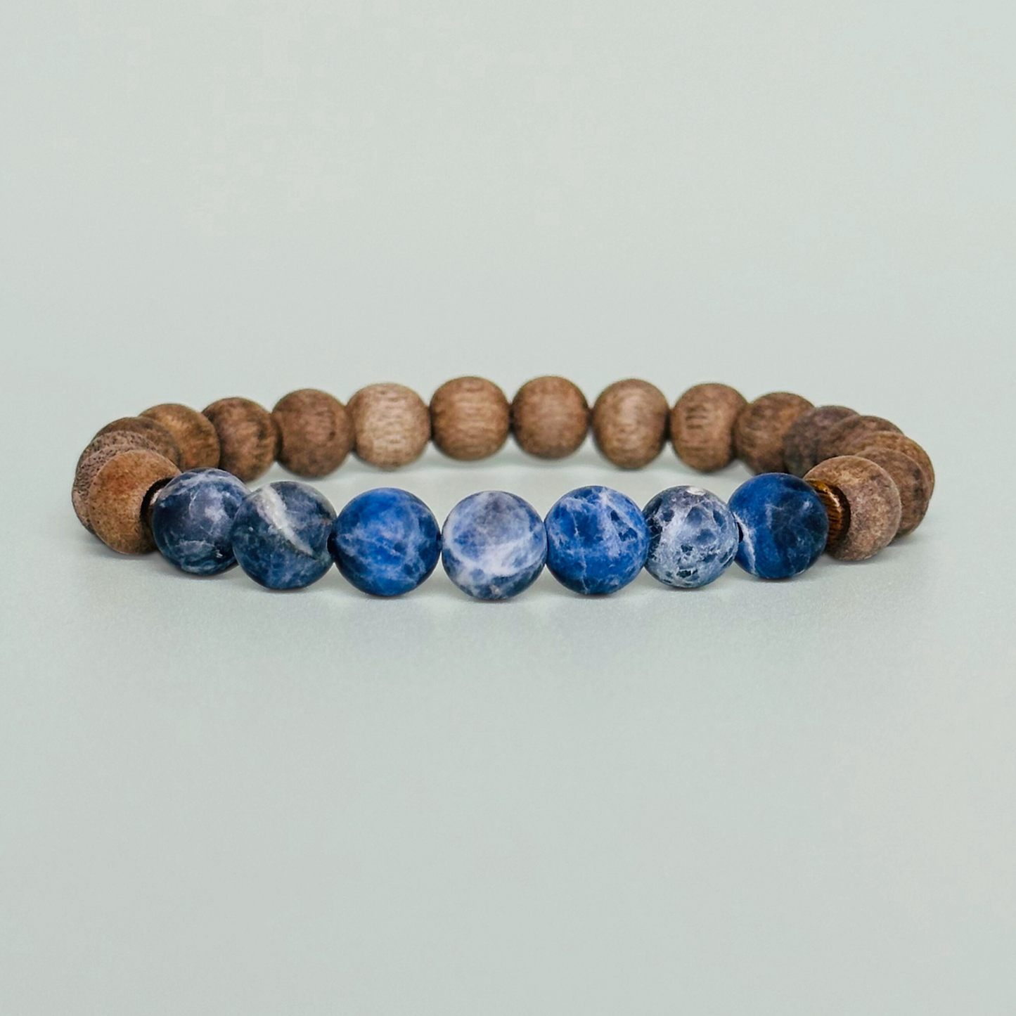 Mens crystal healing bracelet featuring 8mm frosted sodalite beads, grey wood beads and sandalwood spacer beads.