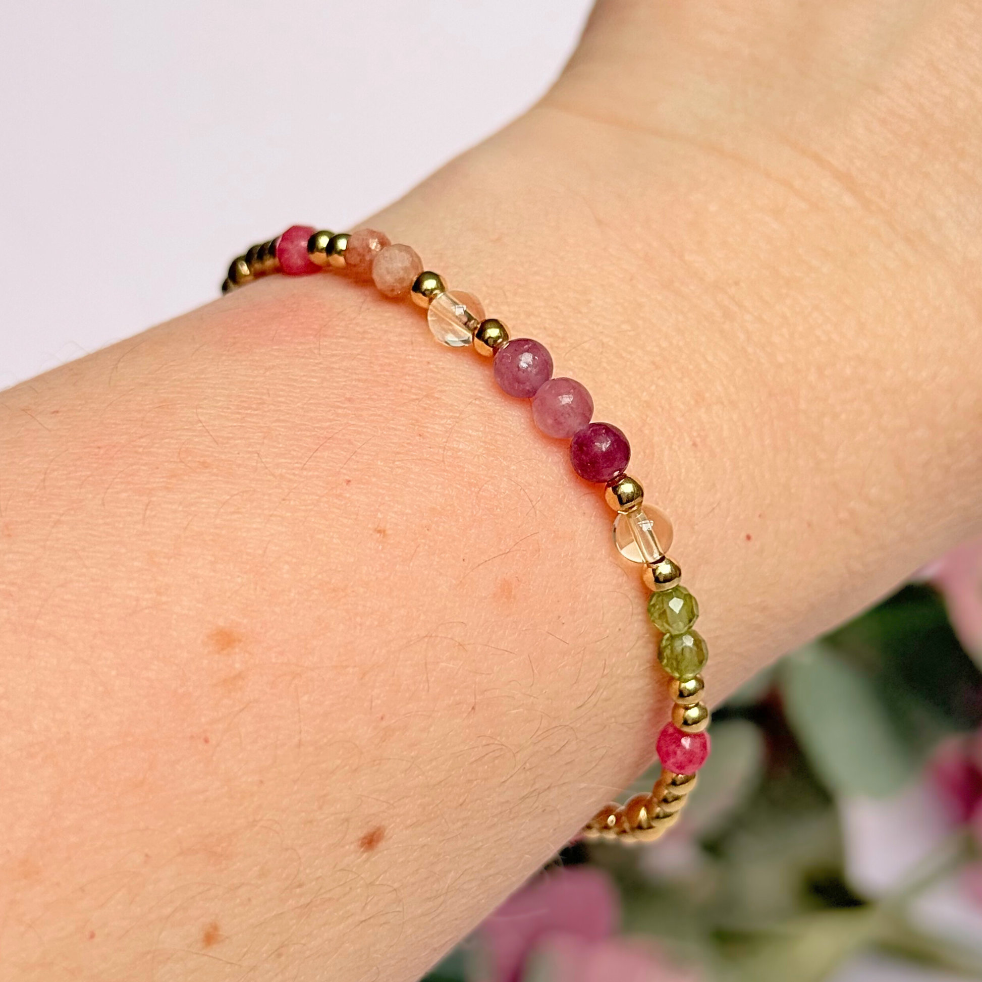 Dainty crystal bracelet featuring a carefully curated selection of genuine crystal beads inspired by wildflowers and free-spirited growth. Featuring 4mm smooth and faceted round gemstone beads with 3mm round accent beads in either sterling silver or gold vermeil. With peridot, sunstone, rhodochrosite, citrine and lepidolite. Picture features the bracelet in gold, being worn.