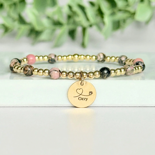 Gold filled bracelet featuring ethically mined 4mm rhodonite crystal beads, separated by 3mm gold filled beads. It features an 11mm gold filled disc charm, which is engraved with a love heart and paw design, which can be personalised with your pet's name. The reverse of the charm says 'Forever in your heart x', although this side can also be personalised with your own words.